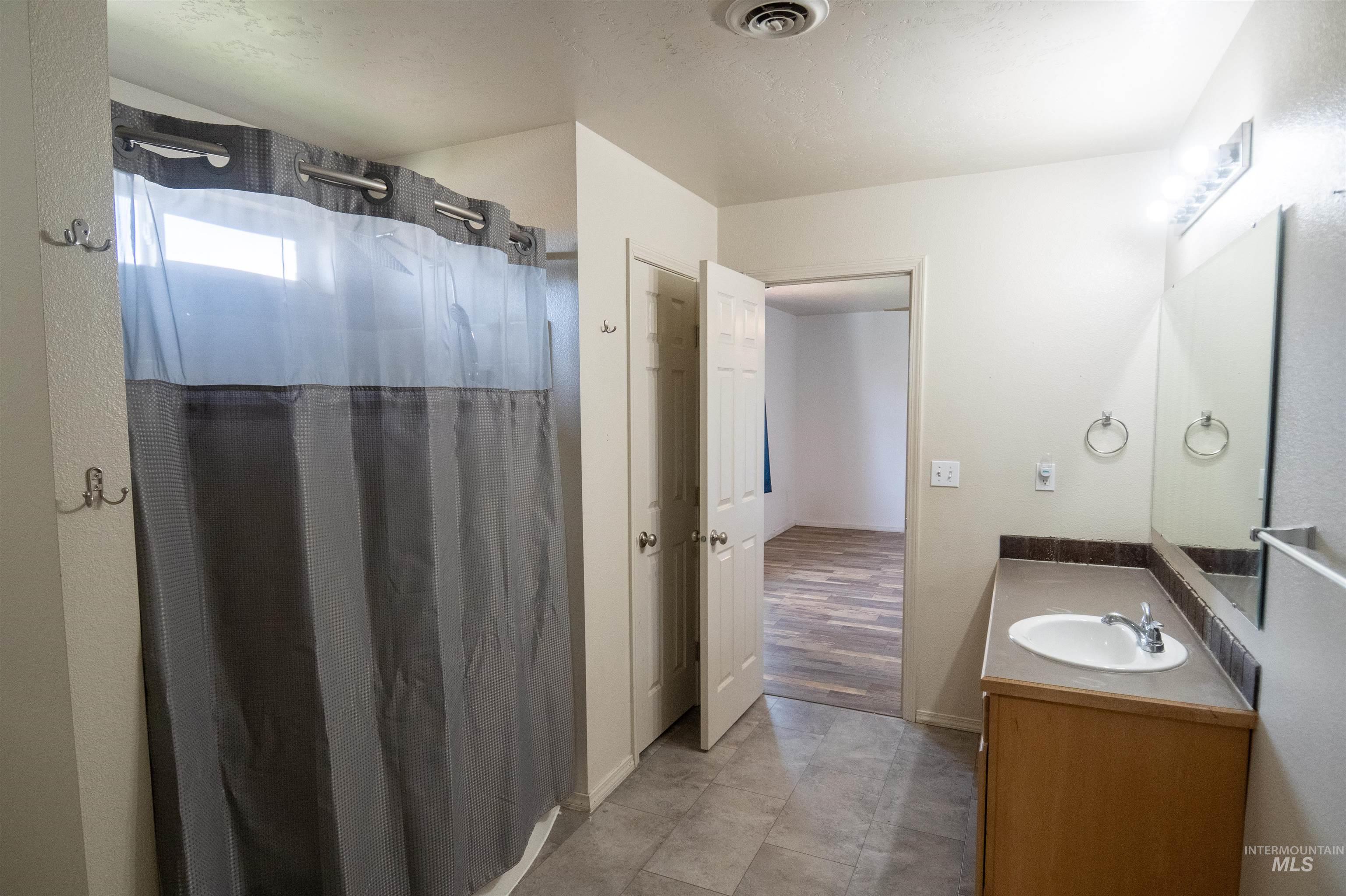 Bathroom featuring a shower stall, vanity, and dark tile patterned flooring
