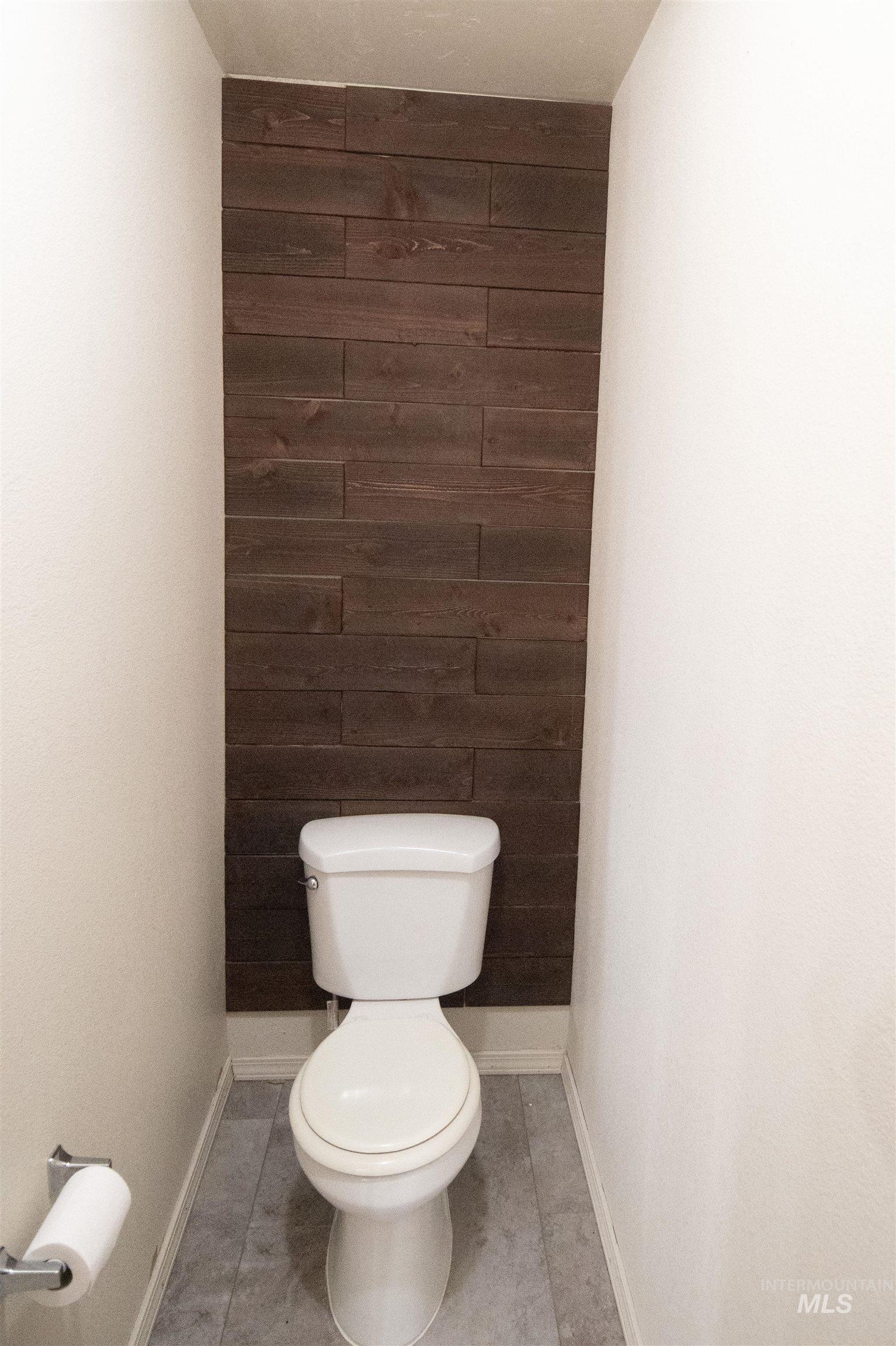 Bathroom featuring wooden walls, light tile patterned flooring, and an accent wall