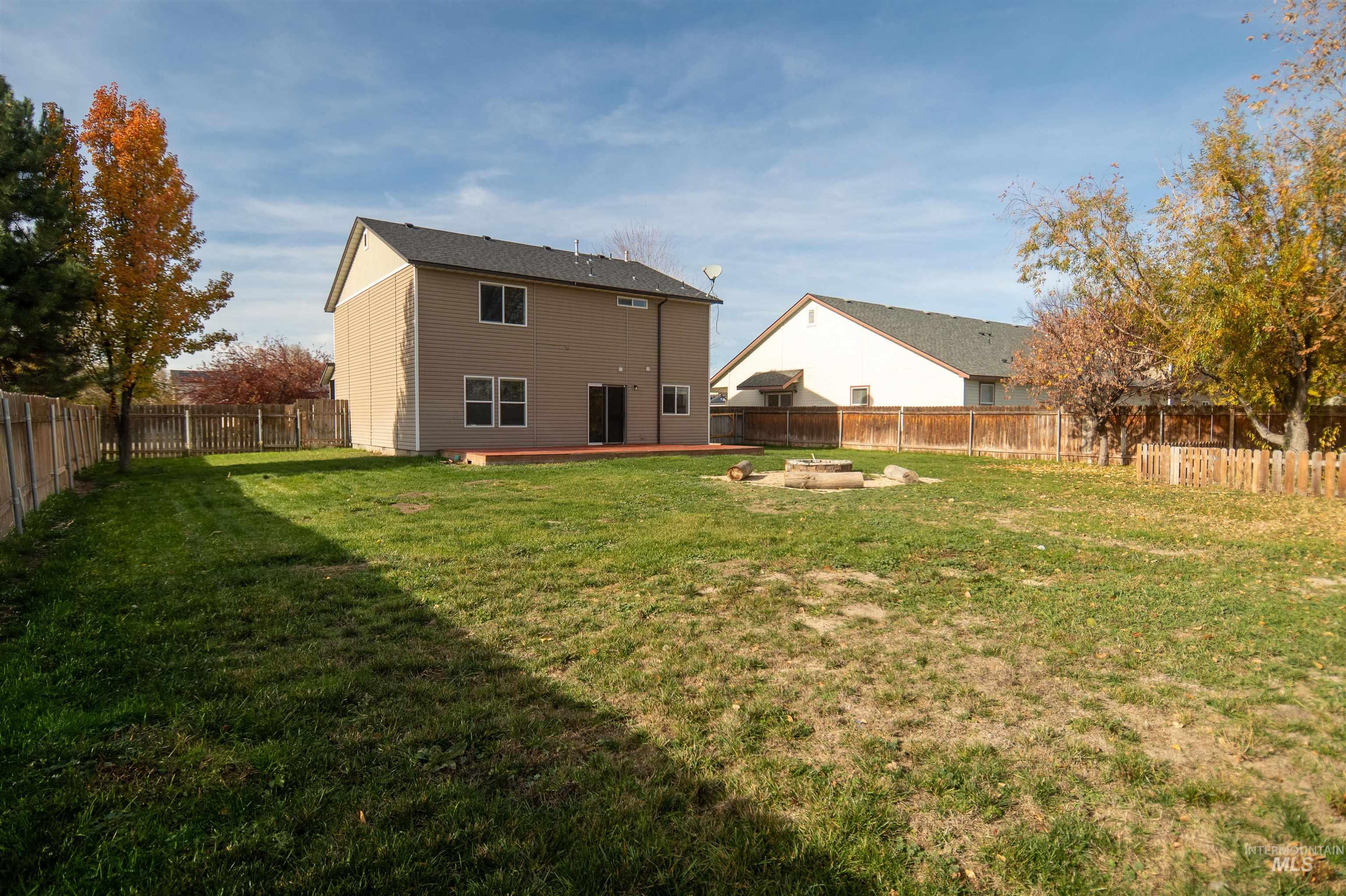 Back of property with a fenced backyard, a patio area, and an outdoor fire pit