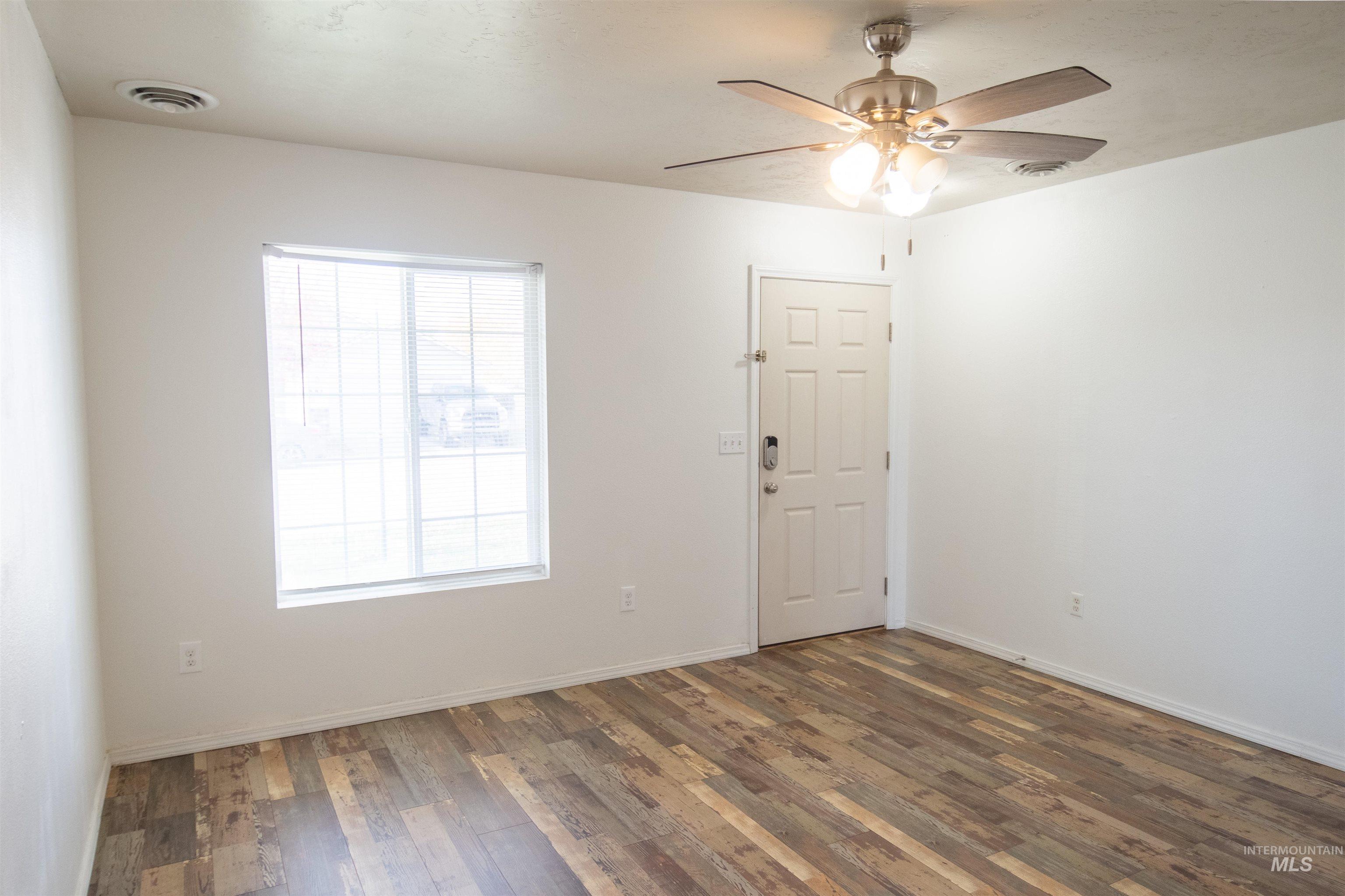 Unfurnished room featuring dark wood-style floors and ceiling fan