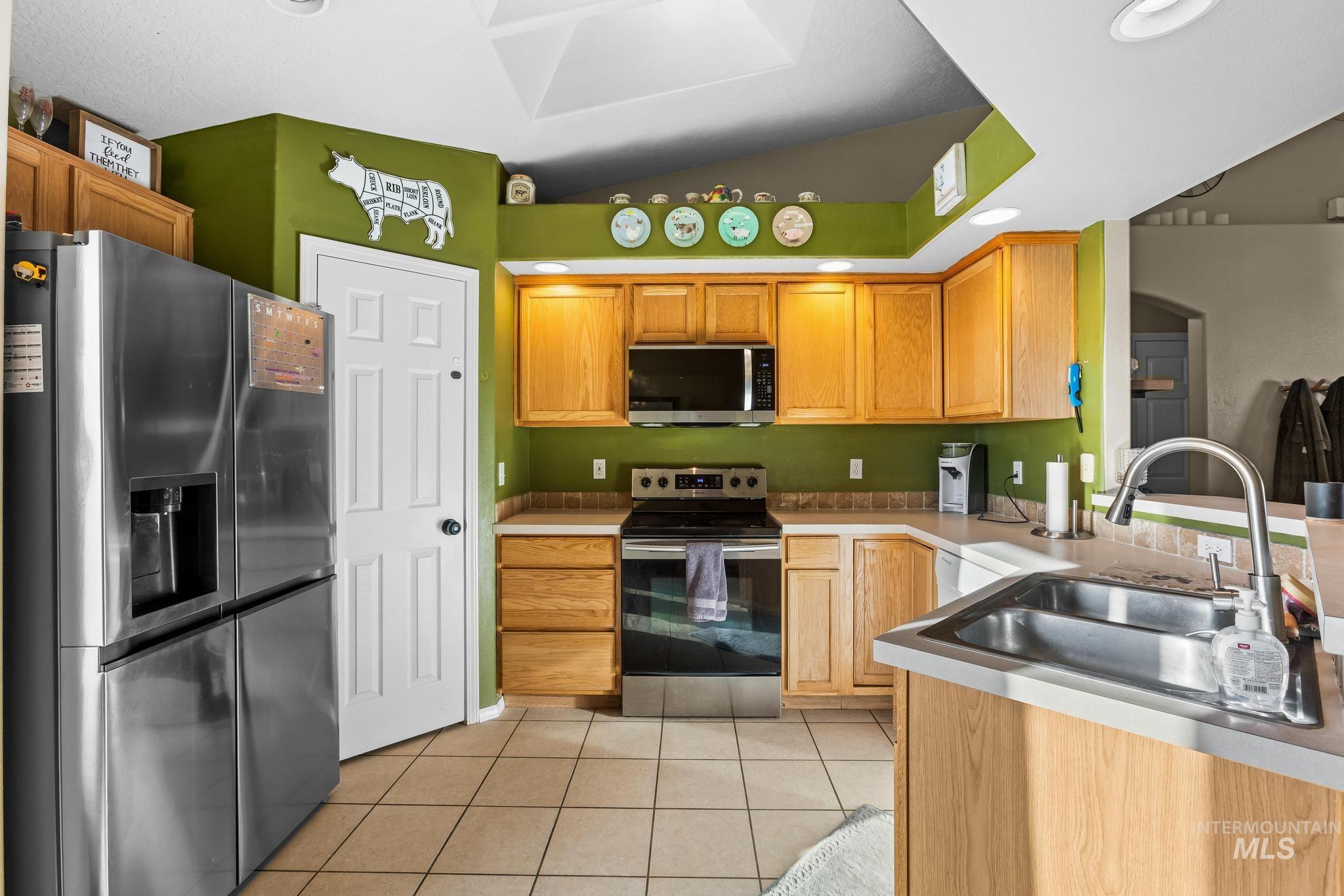 Kitchen with stainless steel appliances, light tile patterned floors, and light countertops