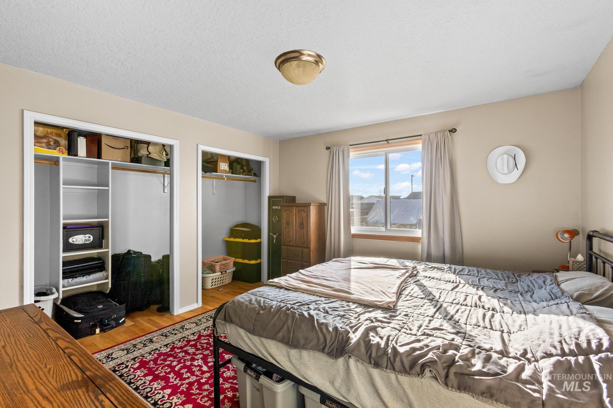 Bedroom with two closets, wood finished floors, and a textured ceiling