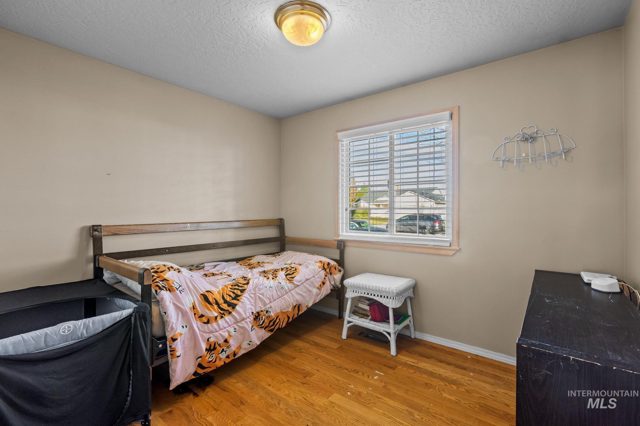 Bedroom with wood finished floors and a textured ceiling