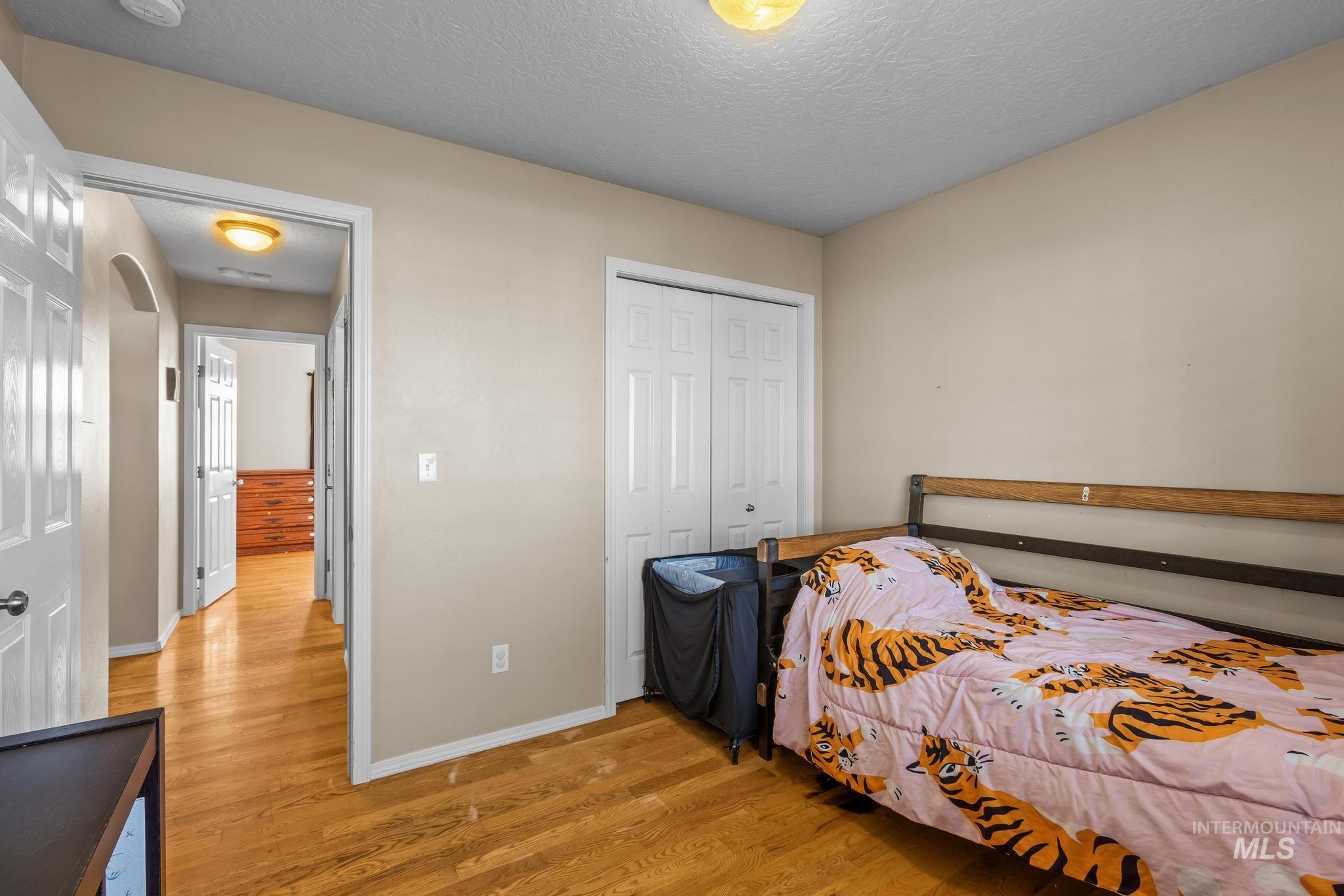 Bedroom with light wood-style flooring, a textured ceiling, and a closet