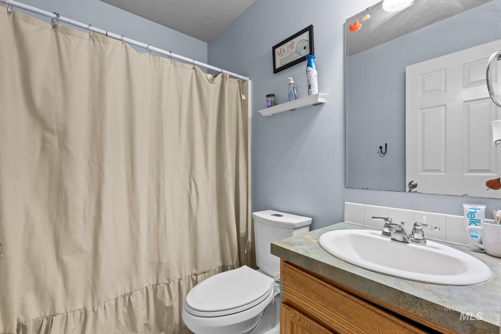 Full bath featuring vanity, curtained shower, and a textured ceiling