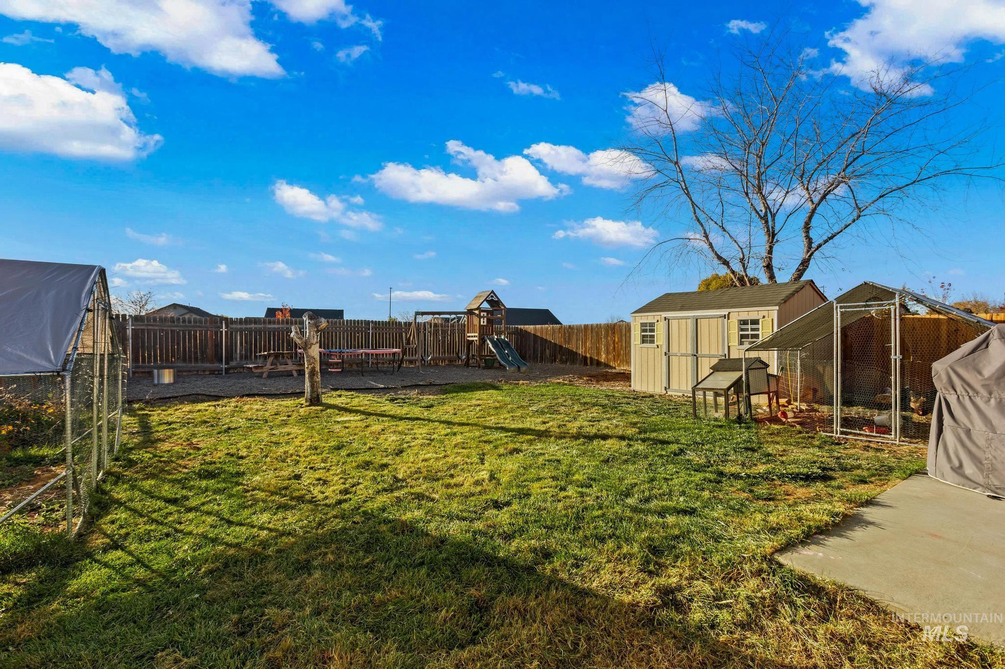 Fenced backyard with exterior structure, a greenhouse, and a storage shed