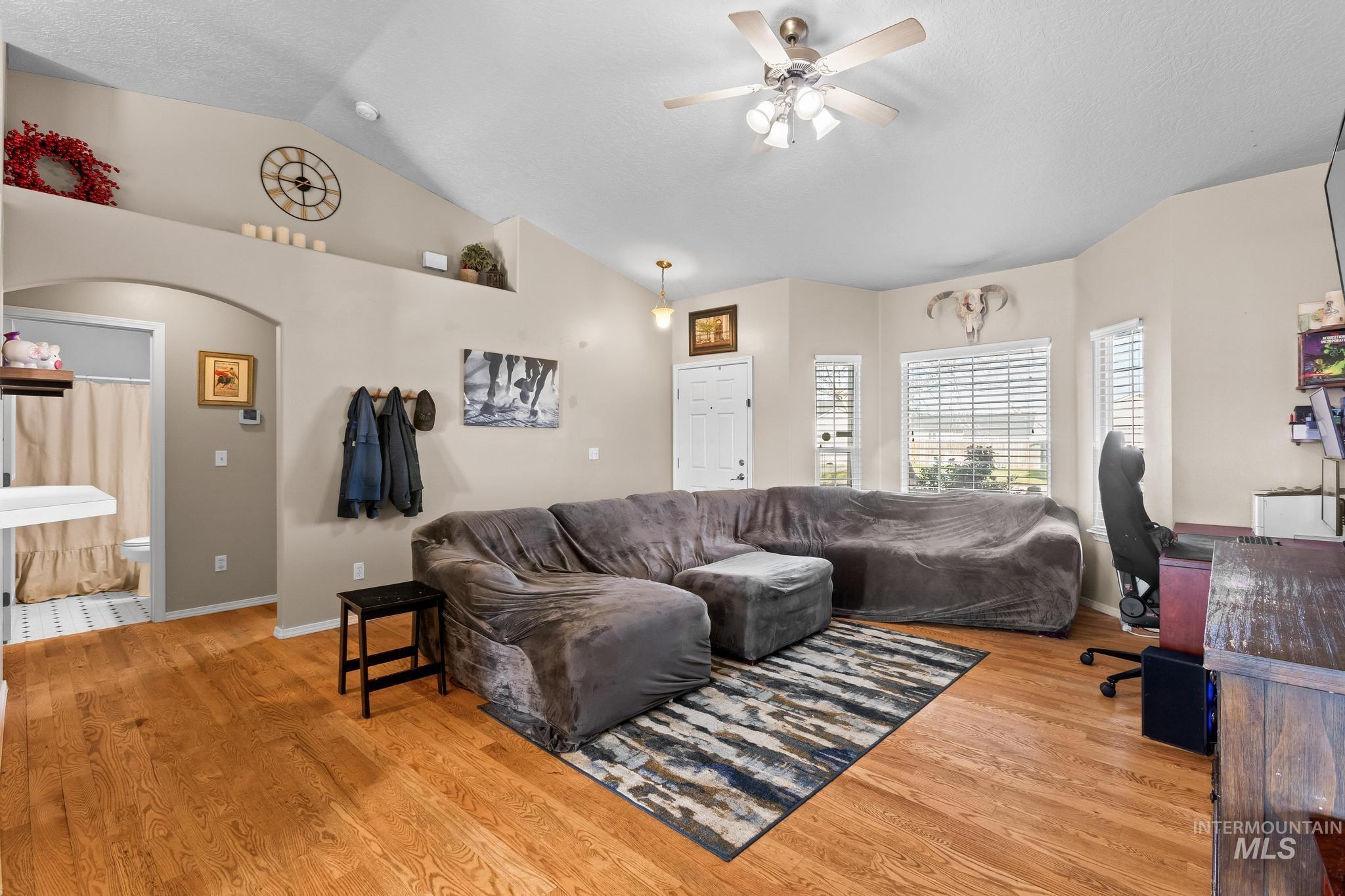 Living area with light wood-style flooring, lofted ceiling, a desk, and a ceiling fan