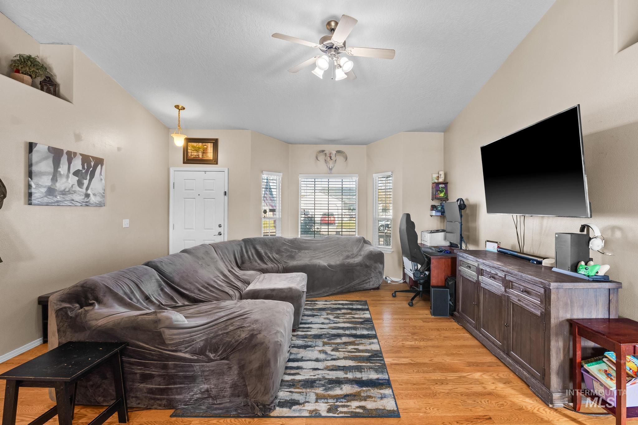 Living area with light wood-style flooring, ceiling fan, and a desk