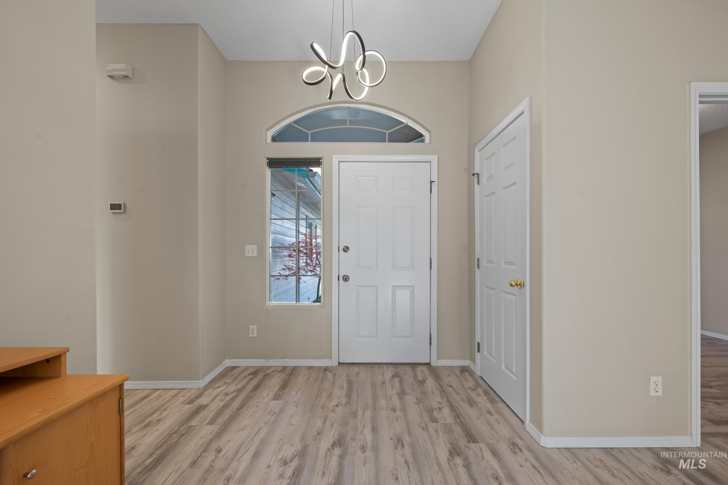 Foyer with light wood-style flooring and a chandelier