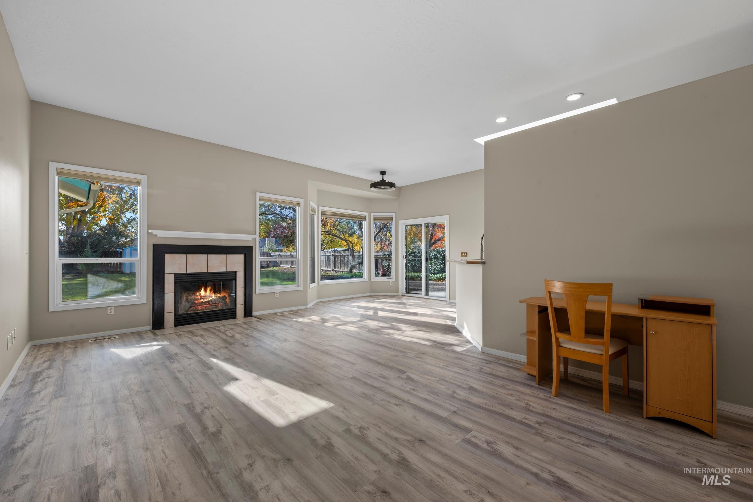 Unfurnished living room featuring recessed lighting, light wood finished floors, and a tile fireplace