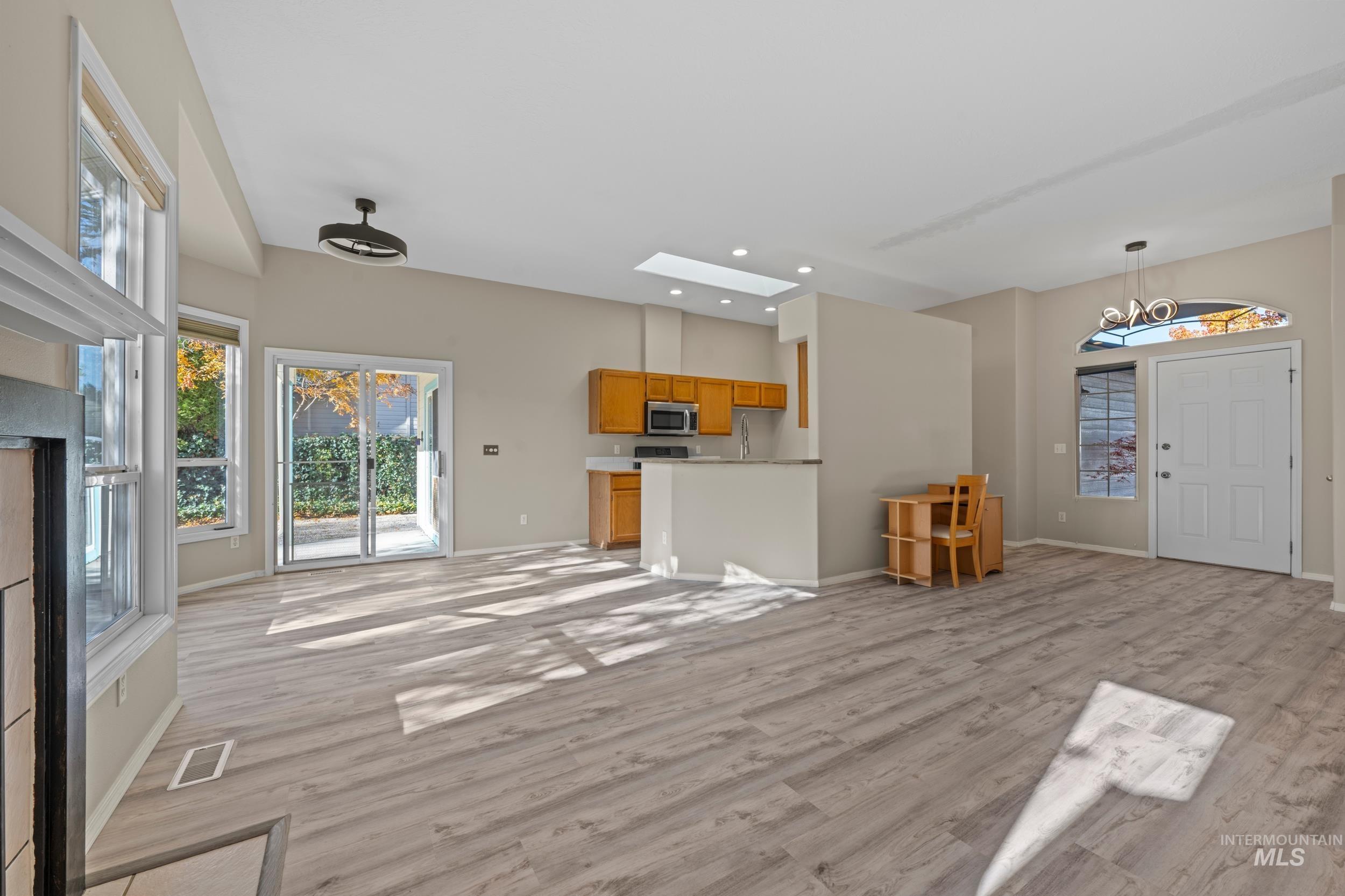 Unfurnished living room with healthy amount of natural light, light wood finished floors, a skylight, and recessed lighting