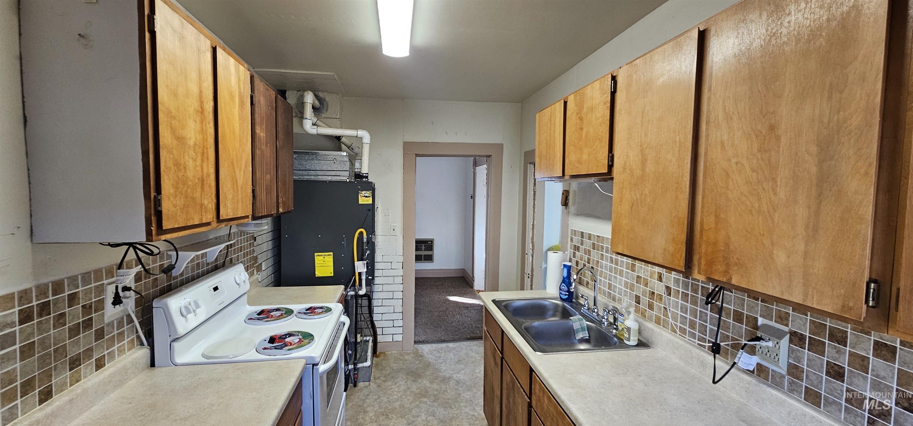 Kitchen featuring tasteful backsplash, white electric range oven, and brown cabinets