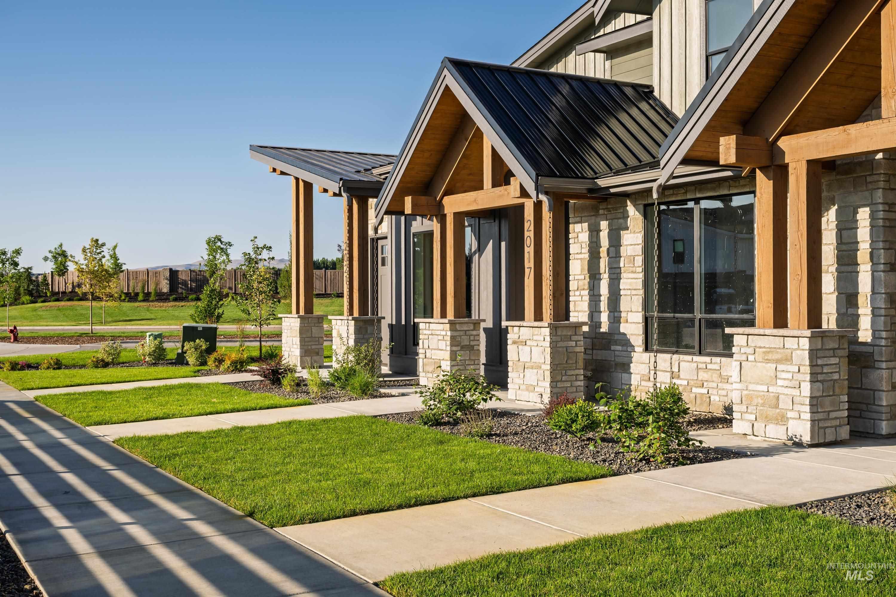 Property entrance featuring stone siding, a lawn, a metal roof, and board and batten siding