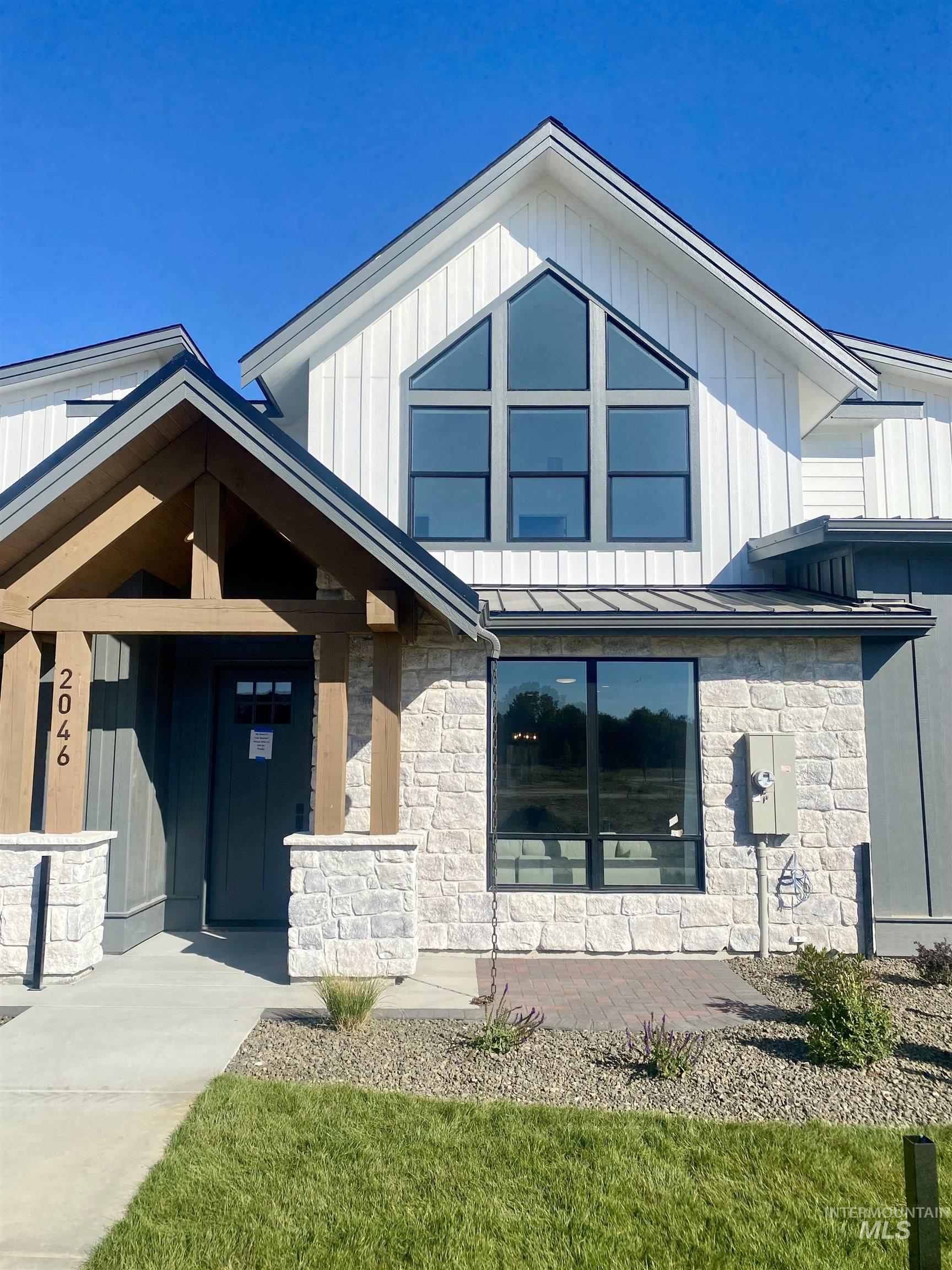 Entrance to property with a standing seam roof, stone siding, a metal roof, and board and batten siding
