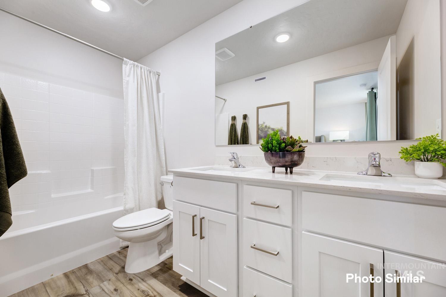 Bathroom with shower / bathtub combination with curtain, light wood-style flooring, double vanity, and recessed lighting