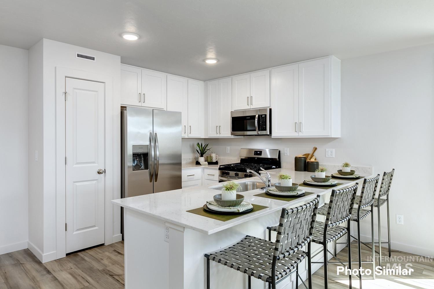 Kitchen featuring a kitchen bar, white cabinetry, light wood finished floors, appliances with stainless steel finishes, and a peninsula
