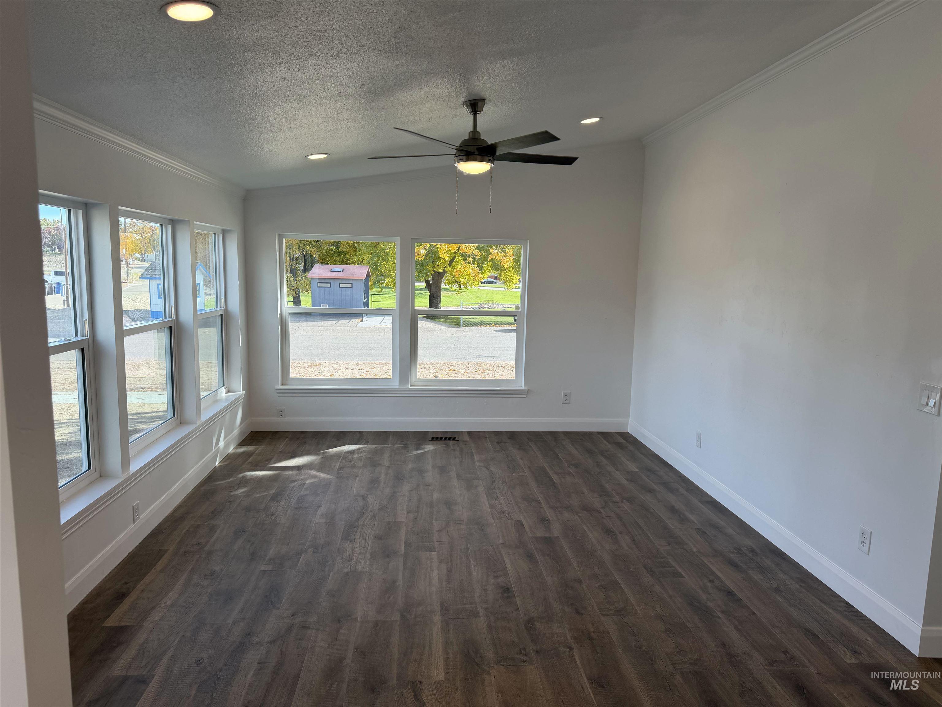 Unfurnished room featuring crown molding, dark wood-style floors, recessed lighting, a textured ceiling, and a ceiling fan