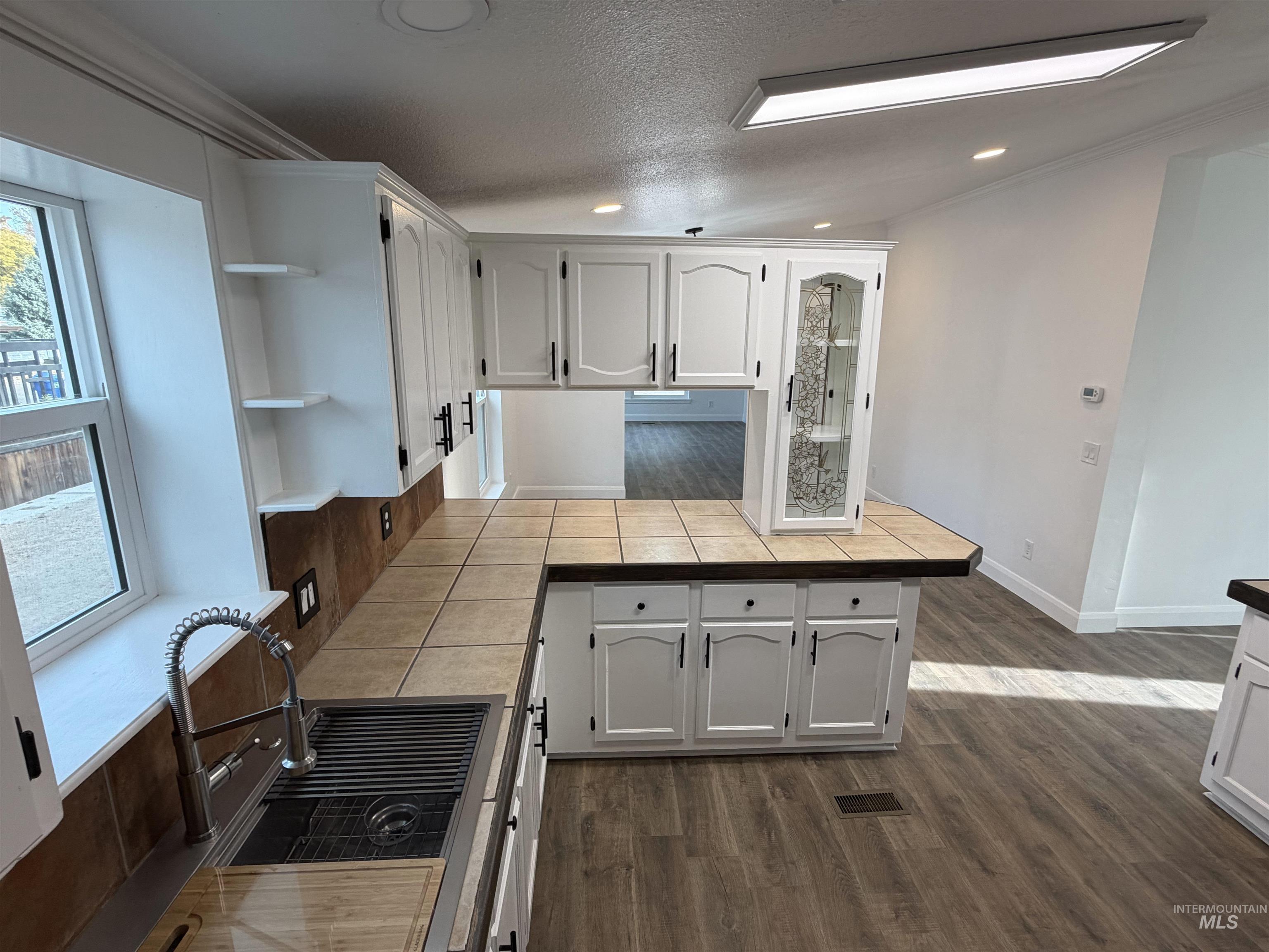 Kitchen featuring white cabinets, a peninsula, dark wood-style floors, open shelves, and a textured ceiling