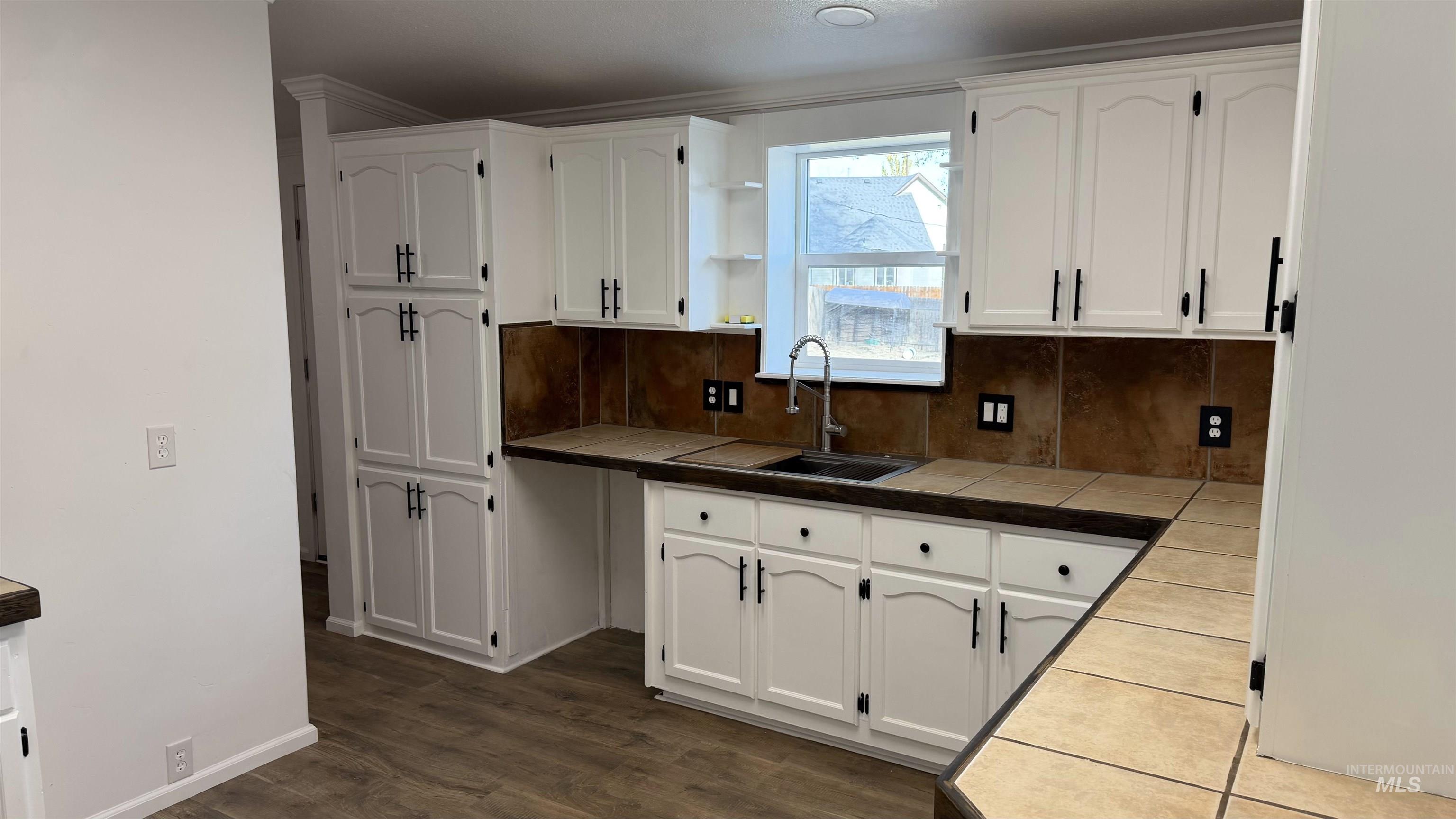 Kitchen featuring tile countertops and white cabinets