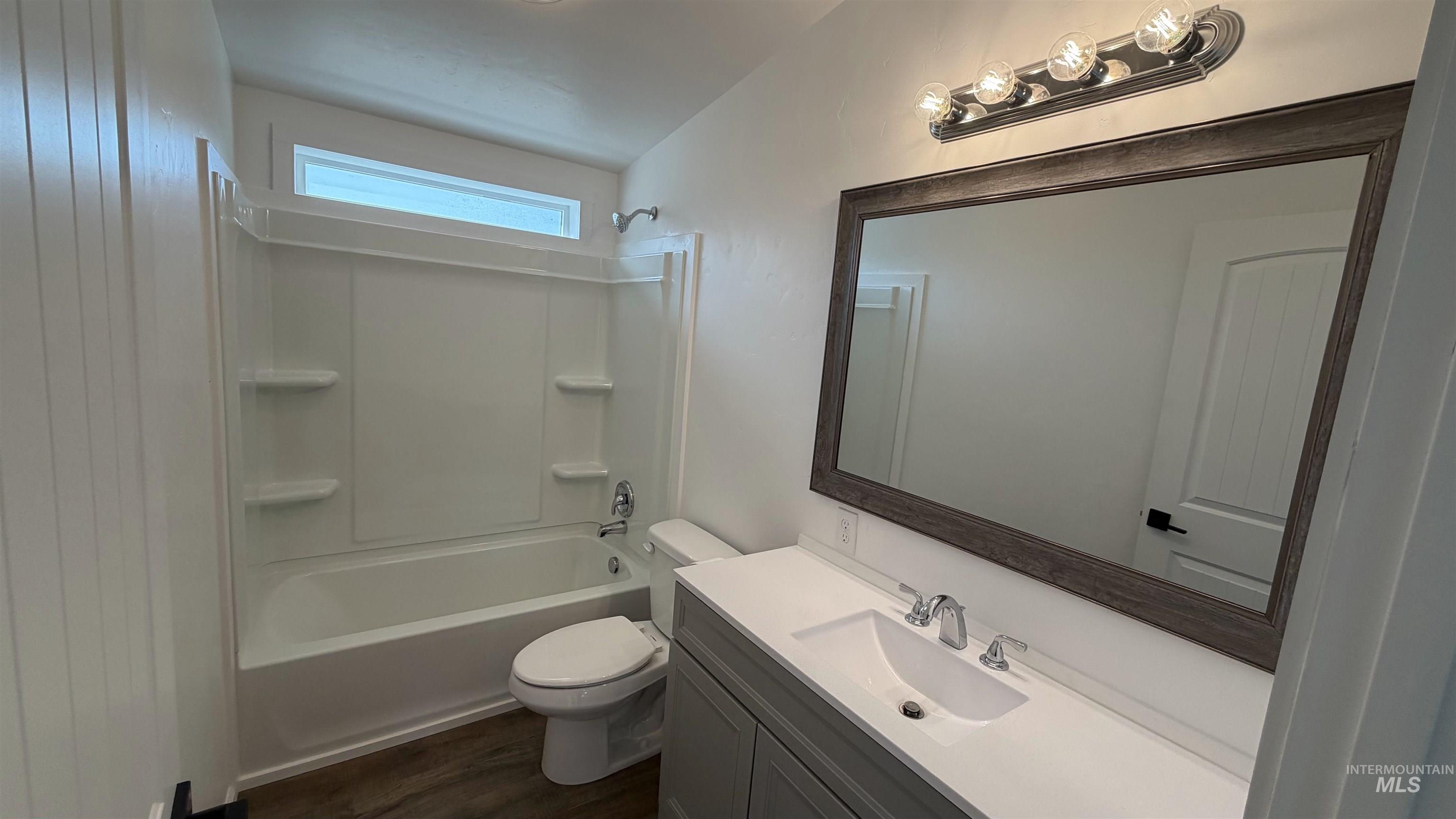 Full bath with tub / shower combination, dark wood-style flooring, vanity, and lofted ceiling