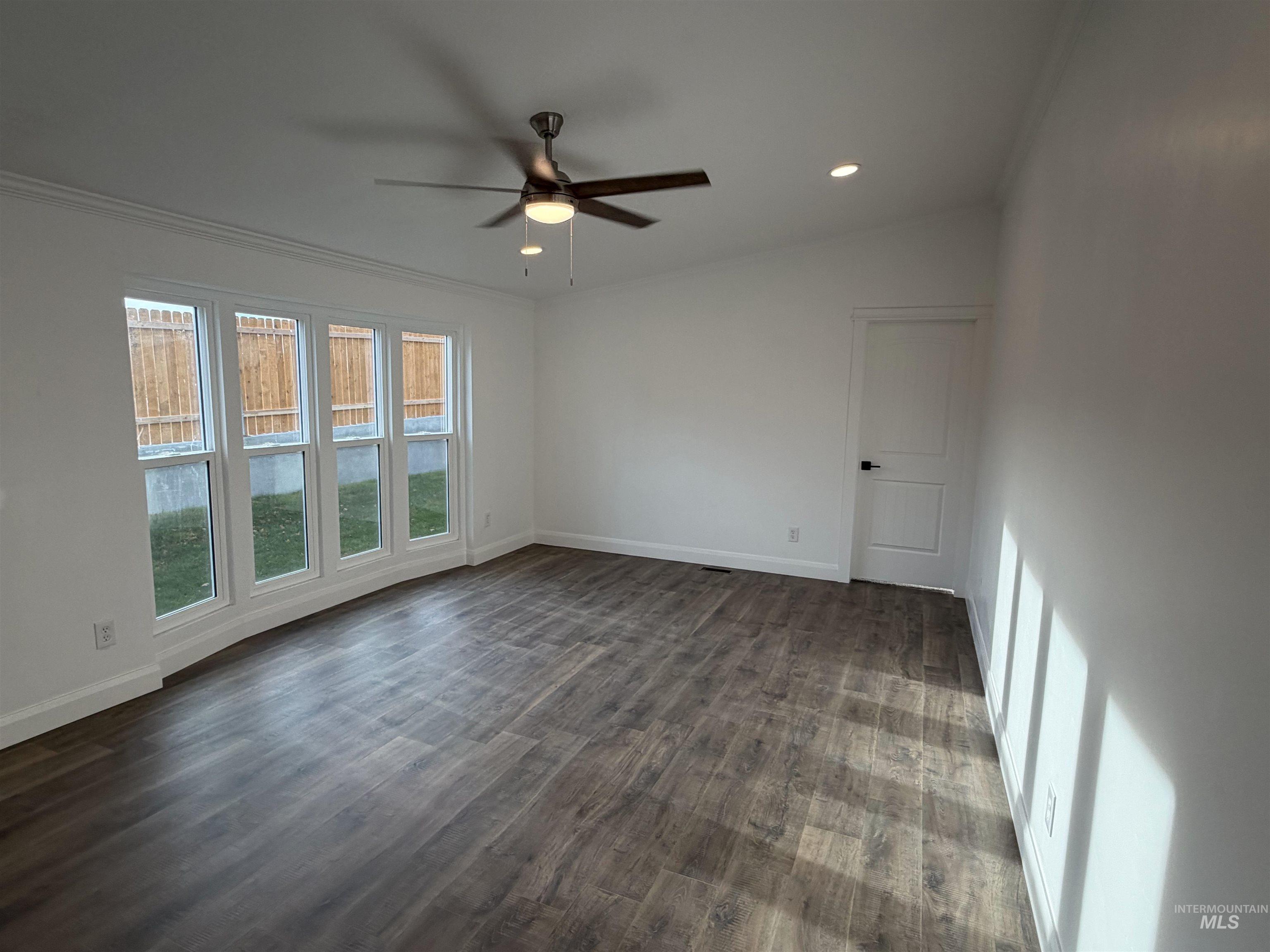Empty room with dark wood-type flooring, recessed lighting, ceiling fan, and ornamental molding