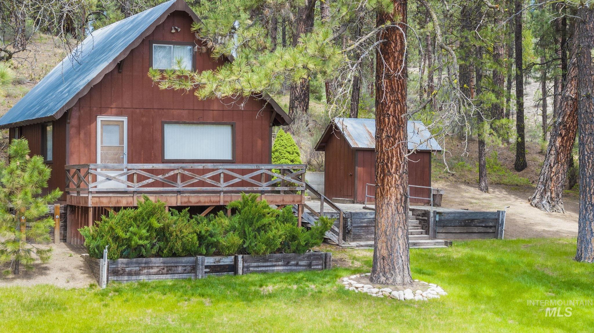 Rear view of property featuring a wooden deck, a metal roof, a storage unit, and a yard