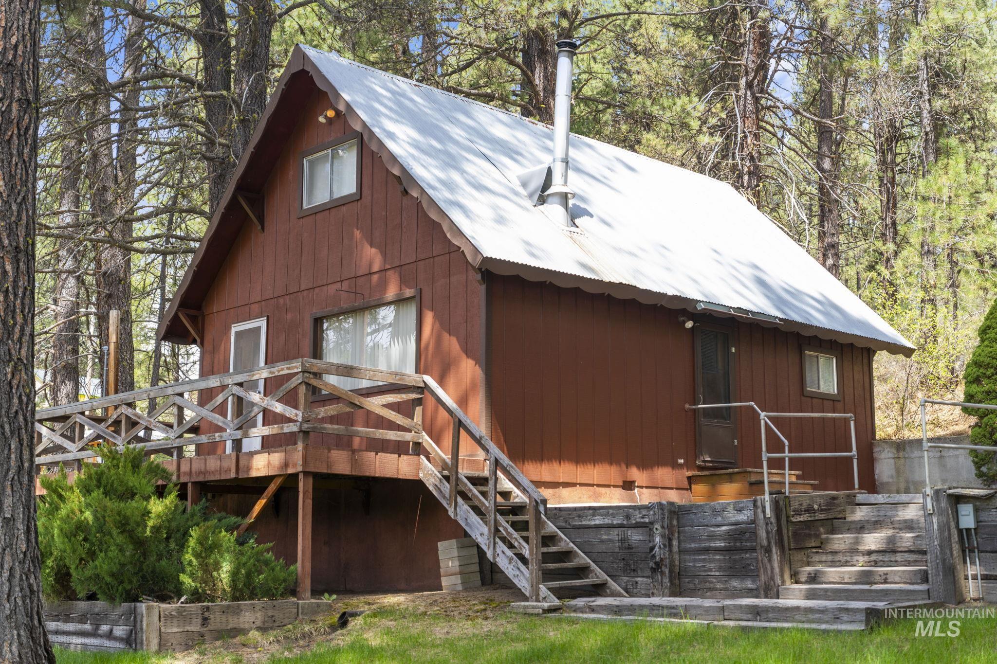 Rear view of house featuring a metal roof, stairs, and a wooden deck