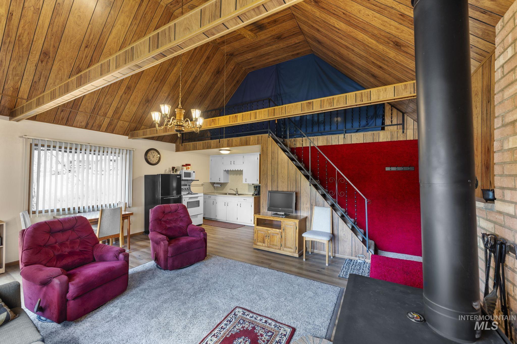 Living area featuring wooden ceiling, wood finished floors, stairs, high vaulted ceiling, and a chandelier