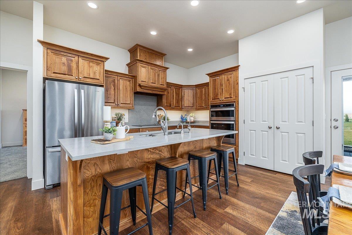 Kitchen featuring wood cabinetry, stainless steel appliances, an island with sink, and recessed lighting