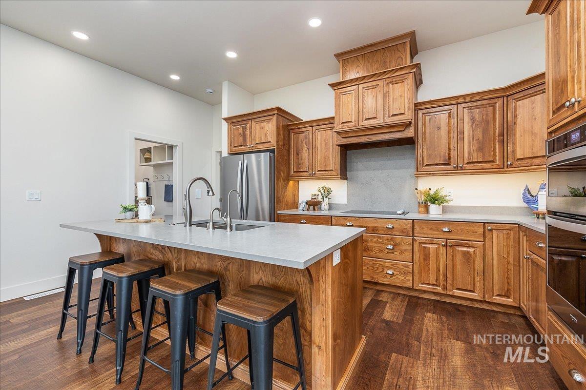 Kitchen featuring wood cabinets, a breakfast bar, dark wood-style floors, and recessed lighting