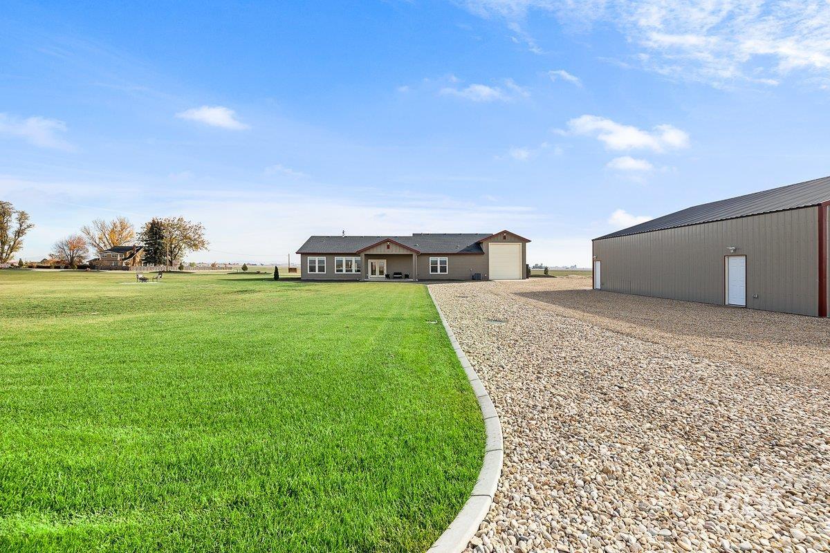 View of green lawn featuring an outdoor structure and driveway