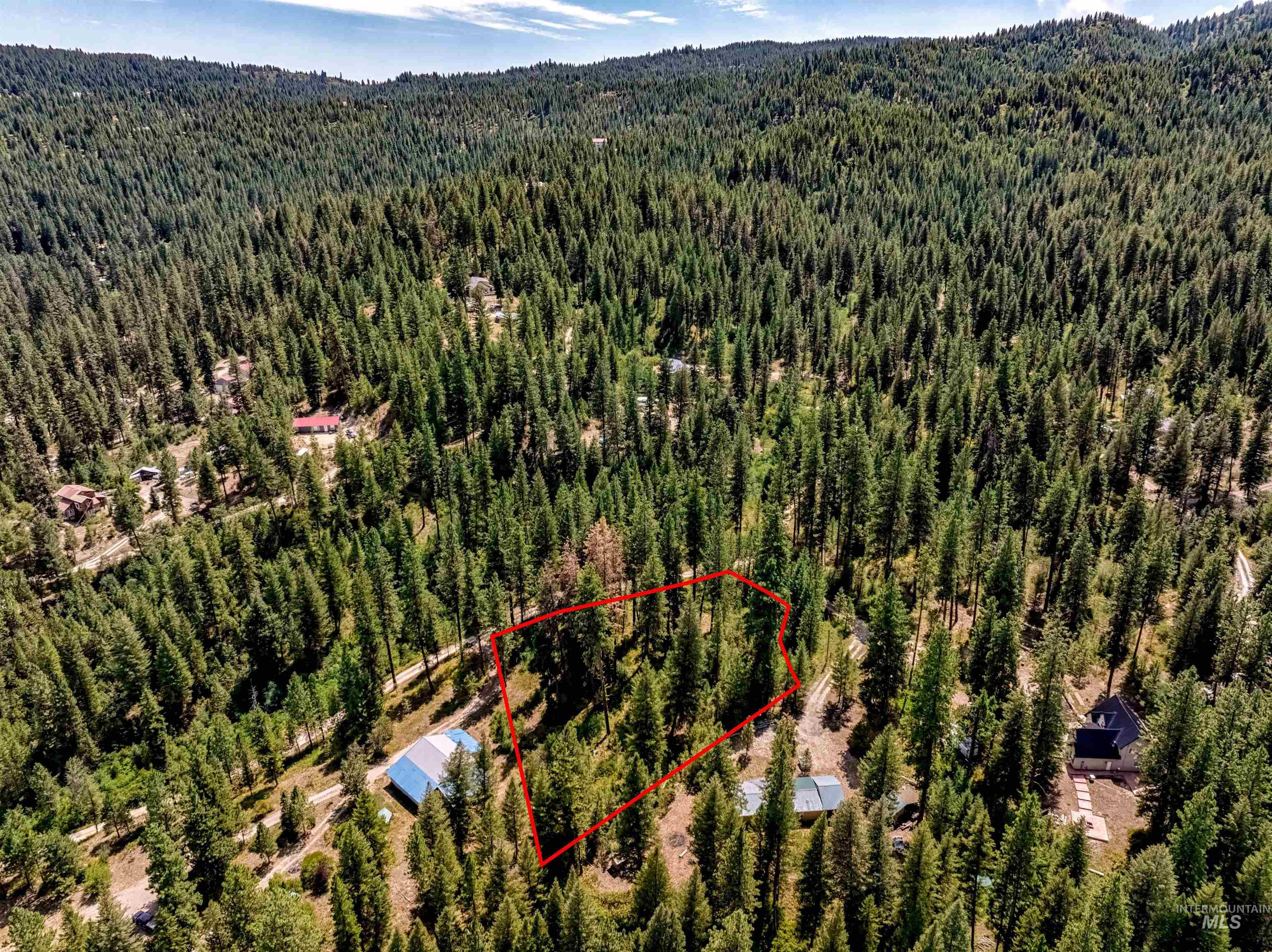 Aerial view of property's location featuring property parcel outlined and a heavily wooded area