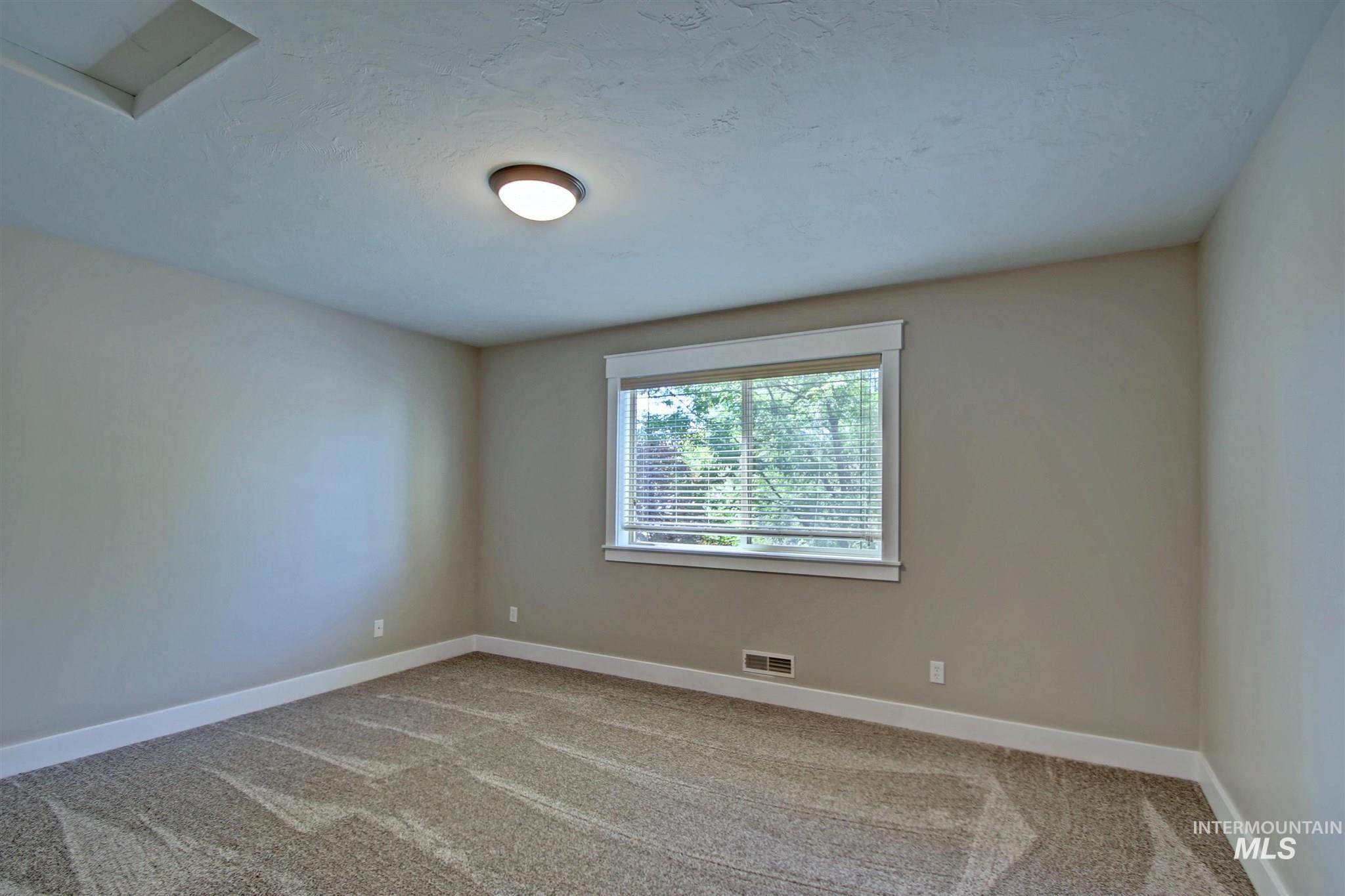 Spare room with baseboards and light colored carpet