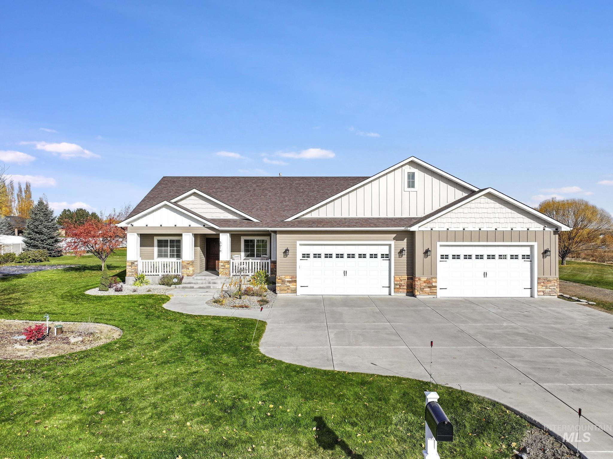 Craftsman inspired home with stone siding, board and batten siding, a shingled roof, covered porch, and a front lawn