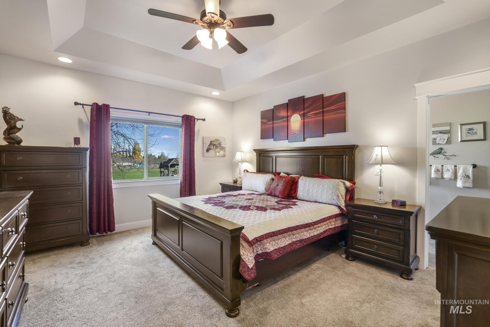 Bedroom featuring light colored carpet, a tray ceiling, a ceiling fan, and recessed lighting