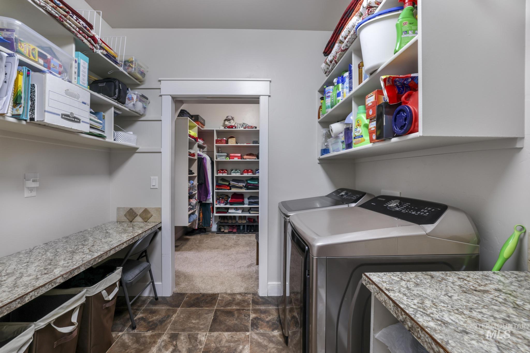 Laundry area featuring washing machine and clothes dryer, dark stone finish floors, and dark carpet