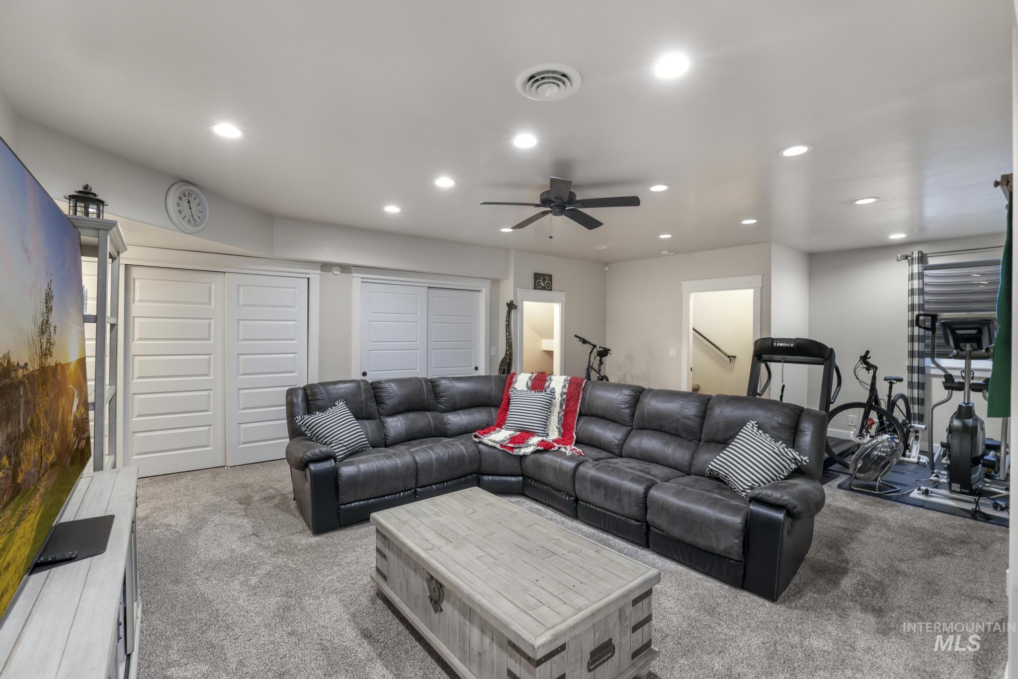 Carpeted living room with recessed lighting and a ceiling fan
