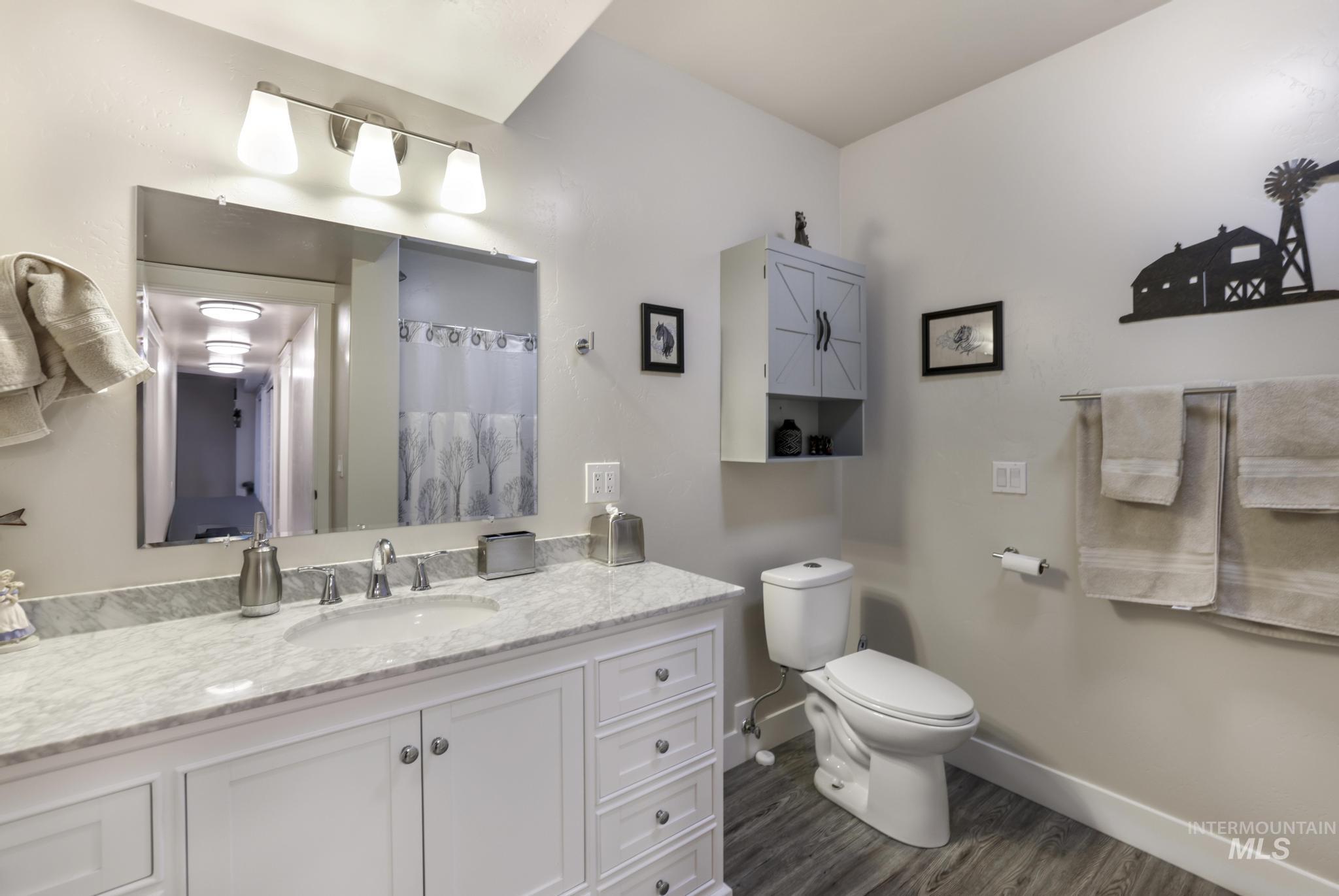 Full bathroom with a shower with shower curtain, vanity, and dark wood-style flooring