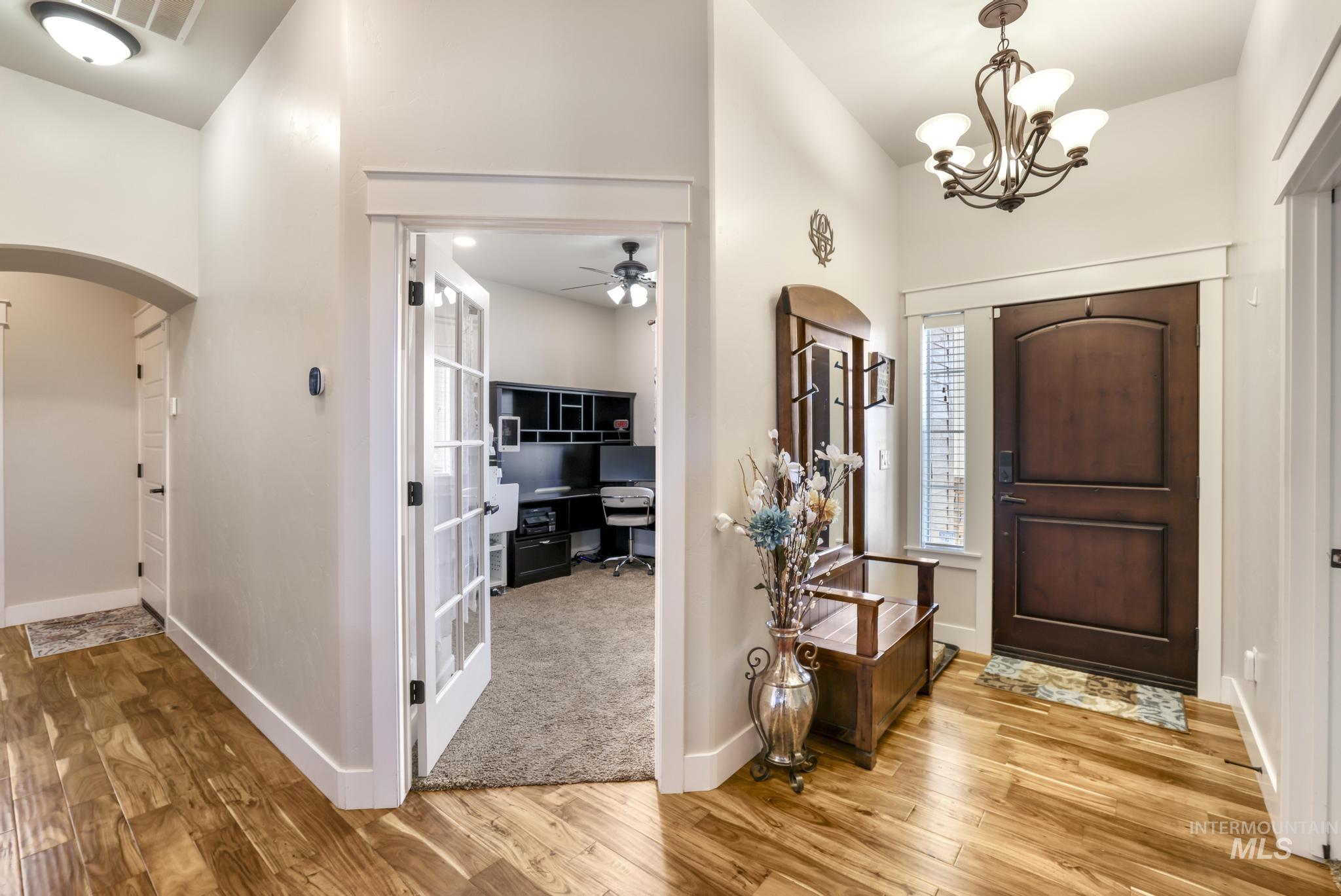 Entrance foyer with arched walkways, a chandelier, light wood-style floors, and a ceiling fan