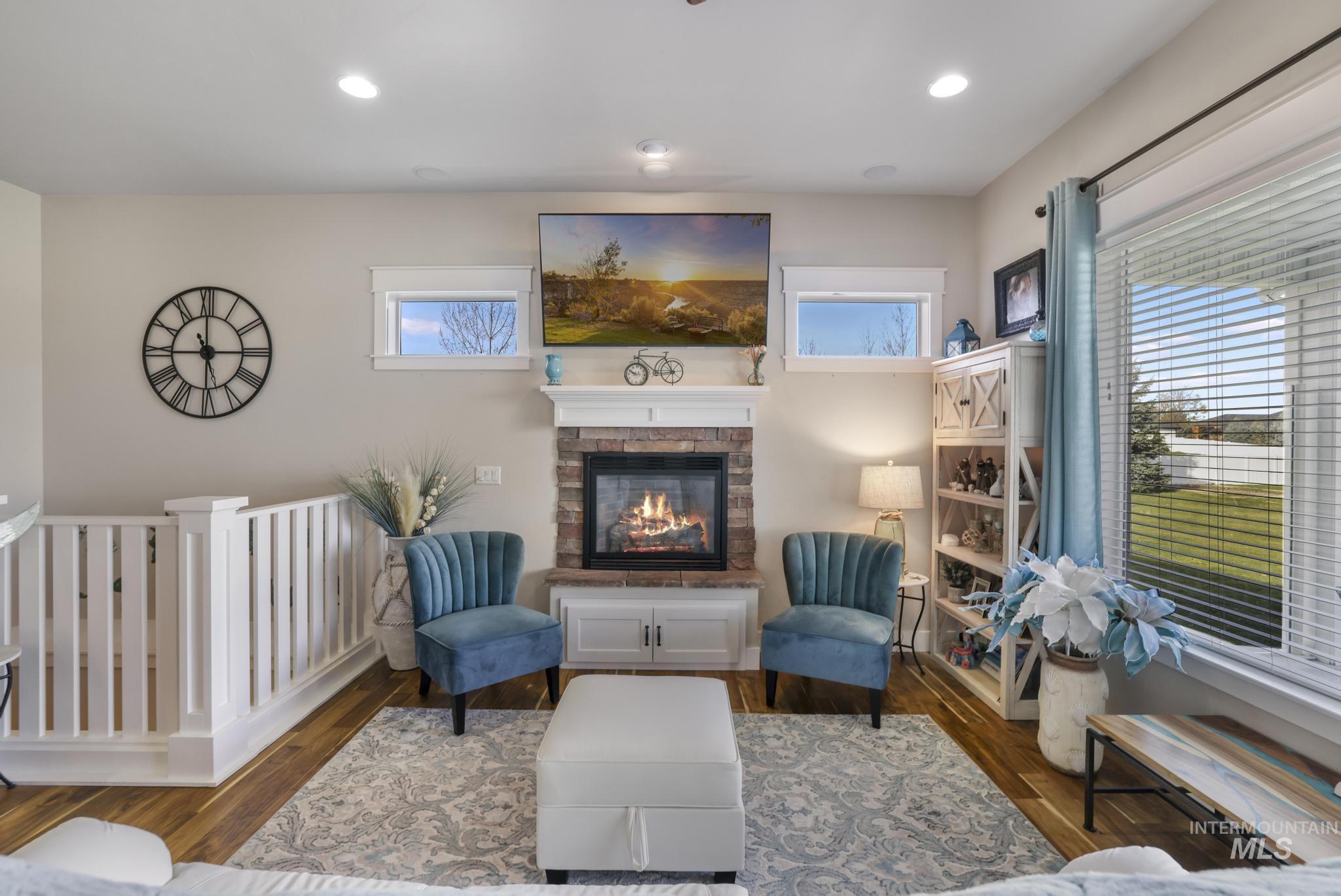 Living area with wood finished floors, a stone fireplace, and recessed lighting
