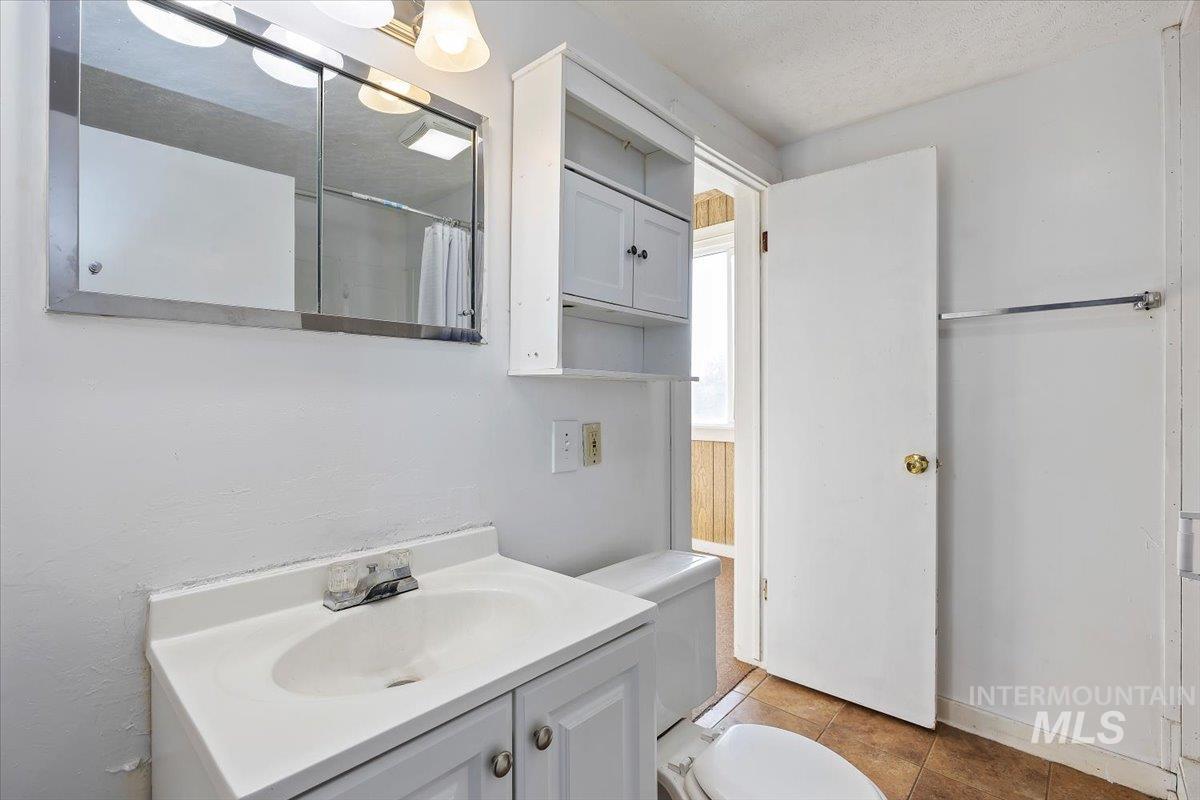 Full bath featuring a shower with curtain, vanity, light tile patterned floors, and a textured ceiling