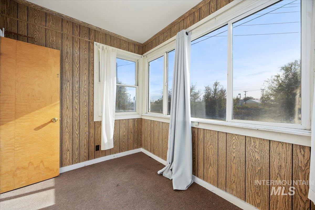 Unfurnished sunroom featuring wooden walls and carpet floors
