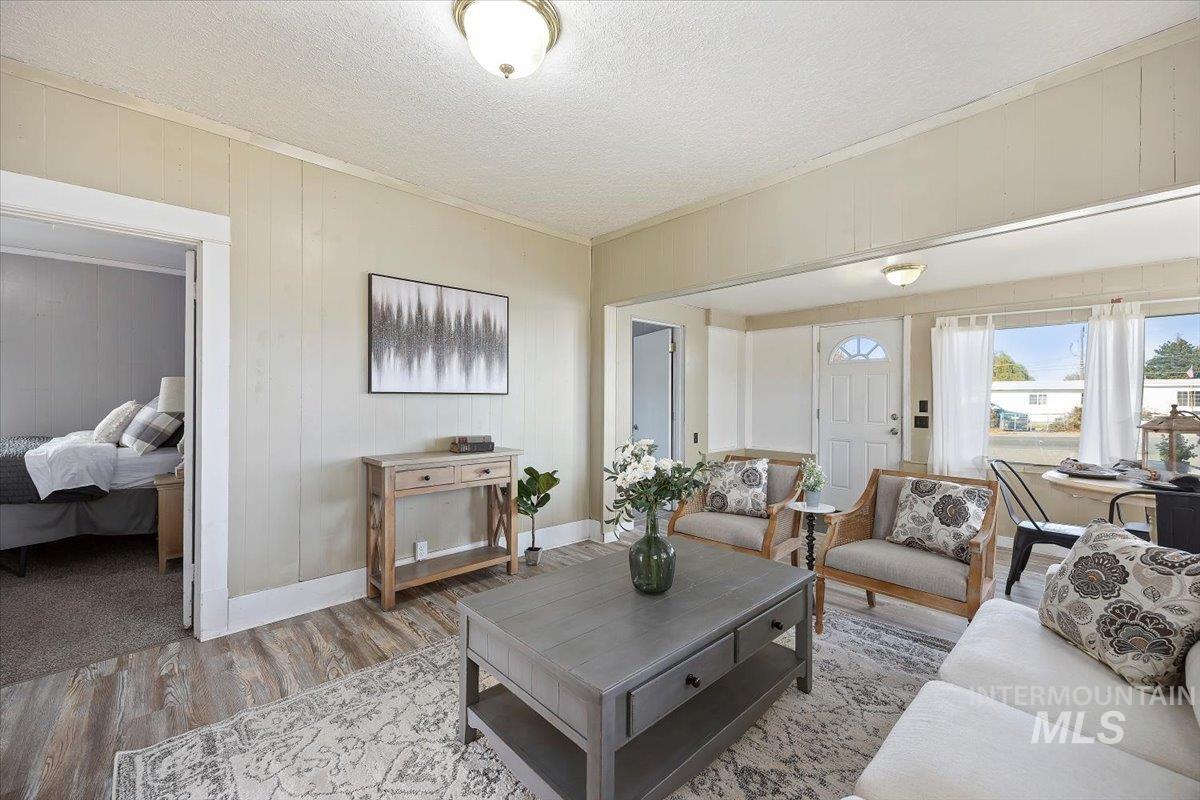 Living area with wood finished floors, a textured ceiling, wood walls, and crown molding