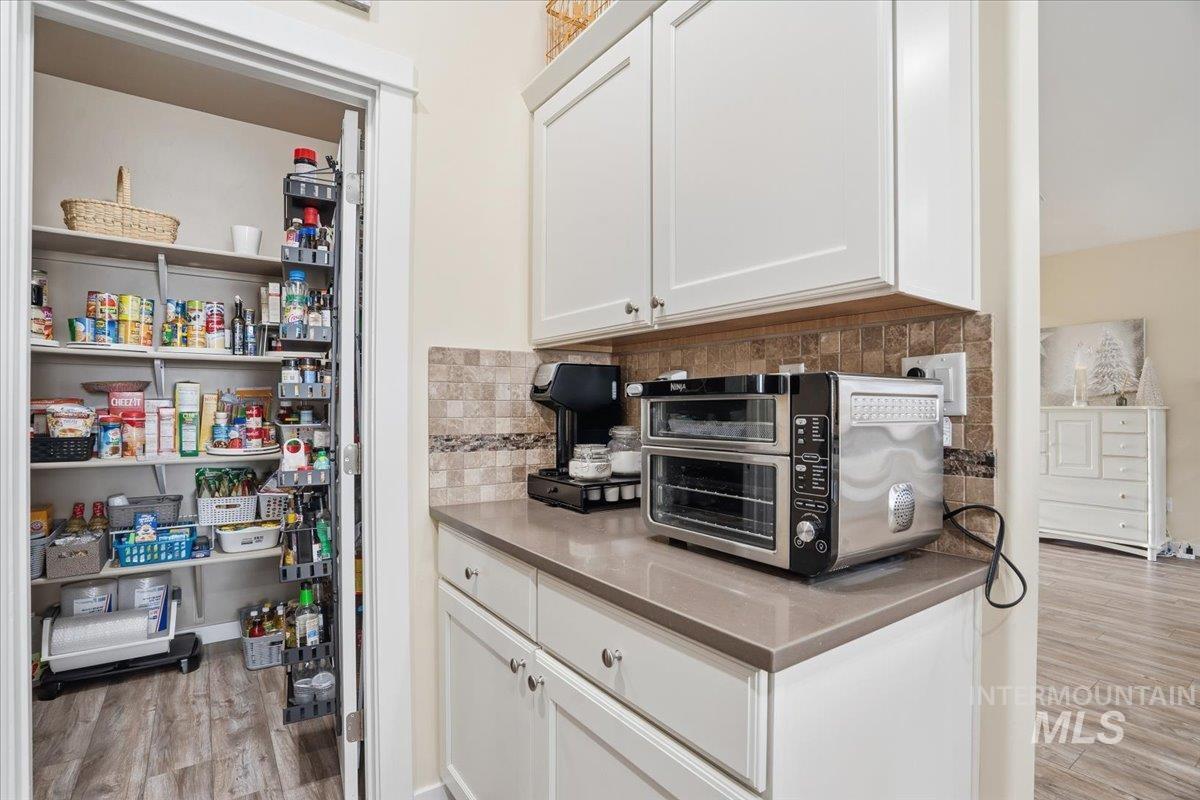 Kitchen featuring tasteful backsplash, light wood-type flooring, and white cabinetry