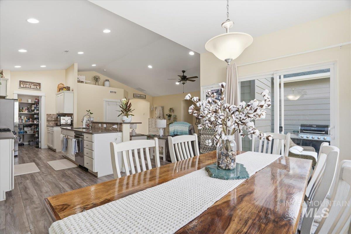 Dining area with dark wood-style flooring, lofted ceiling, a ceiling fan, and recessed lighting