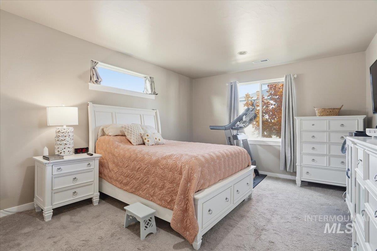 Bedroom with light colored carpet and multiple windows