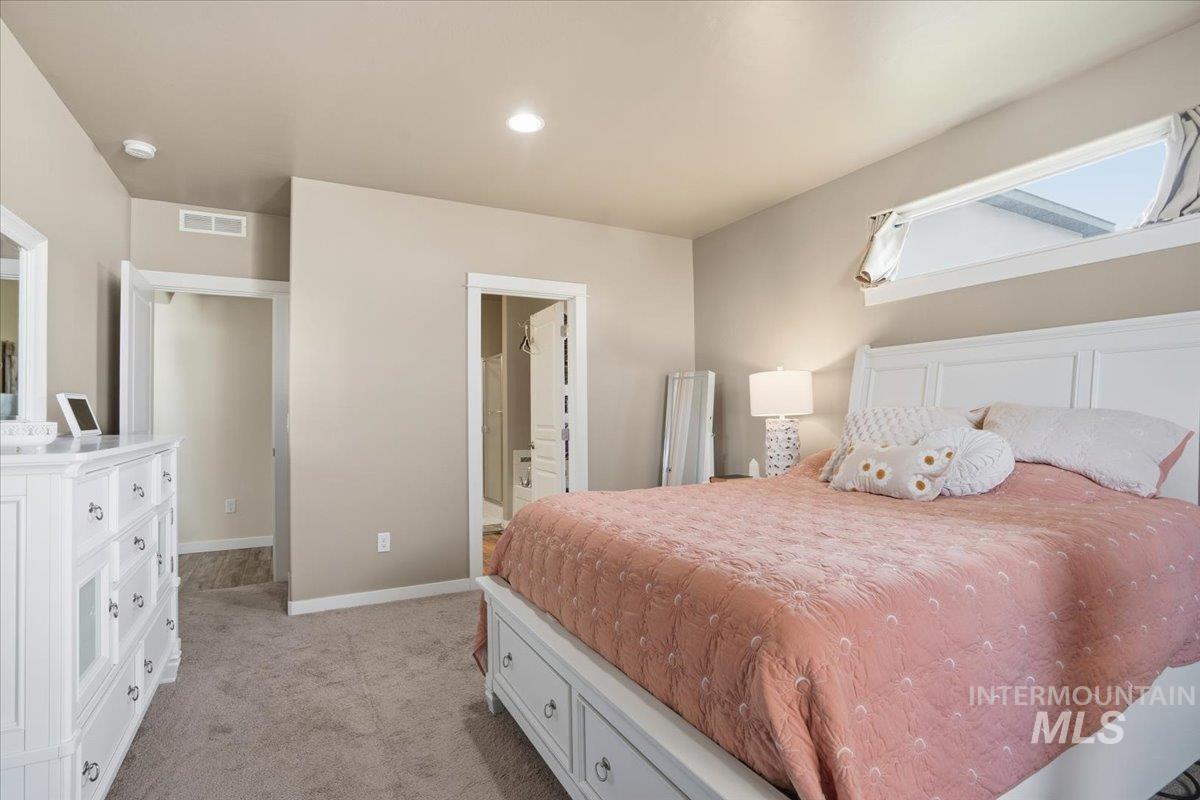 Bedroom with light carpet, ensuite bathroom, and recessed lighting