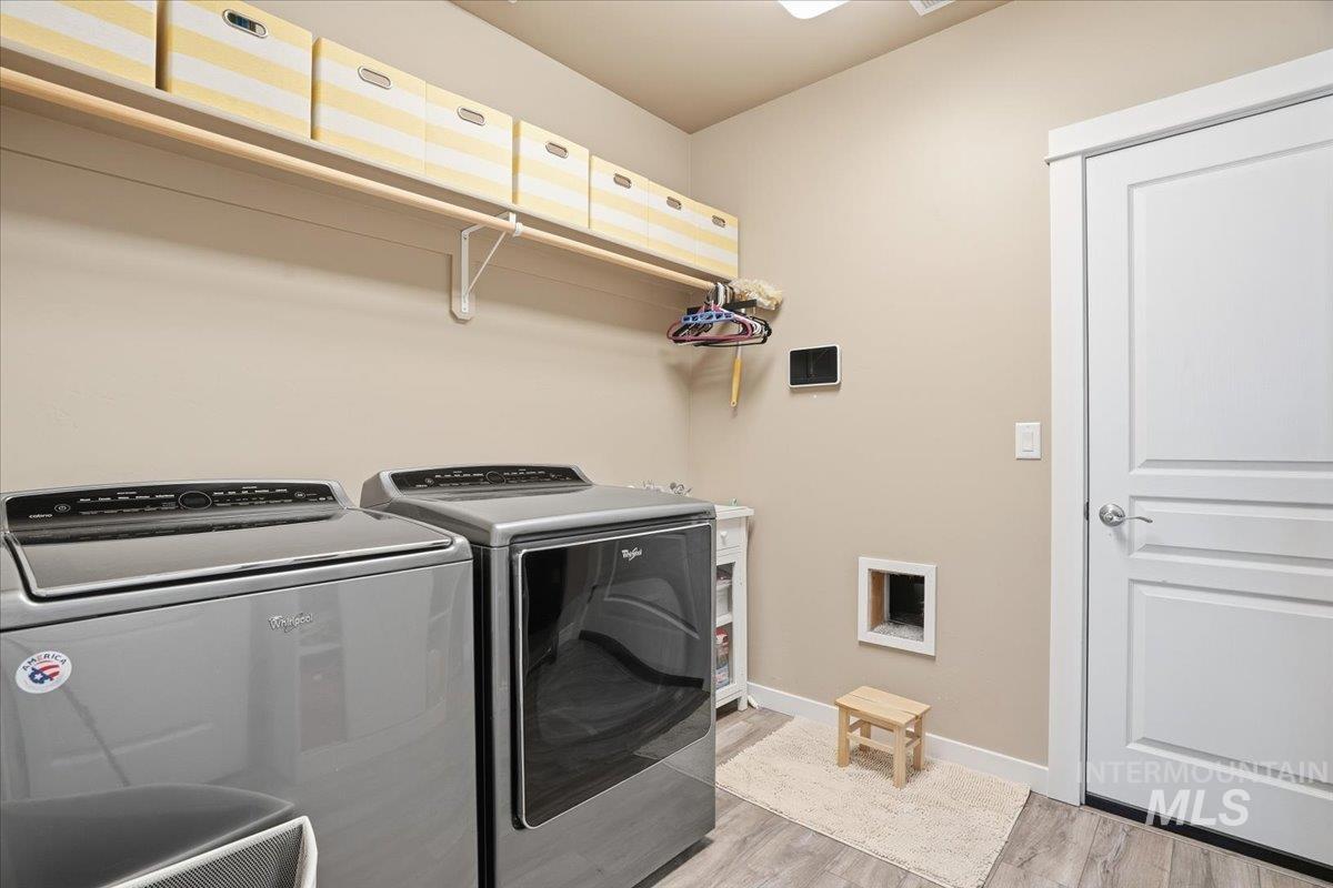 Laundry room with light wood finished floors and washing machine and dryer