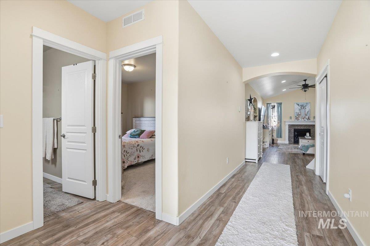 Corridor featuring light wood finished floors, vaulted ceiling, arched walkways, and recessed lighting