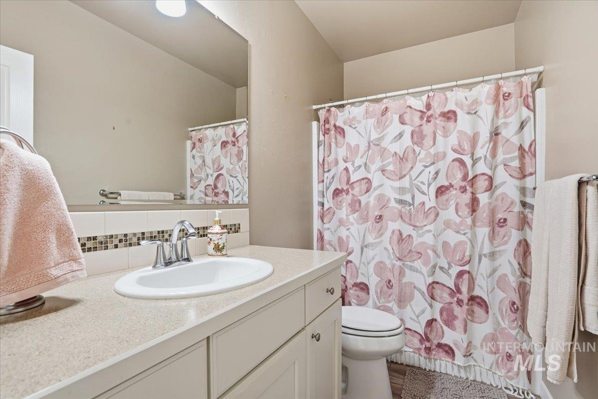 Full bathroom featuring vanity, curtained shower, and backsplash